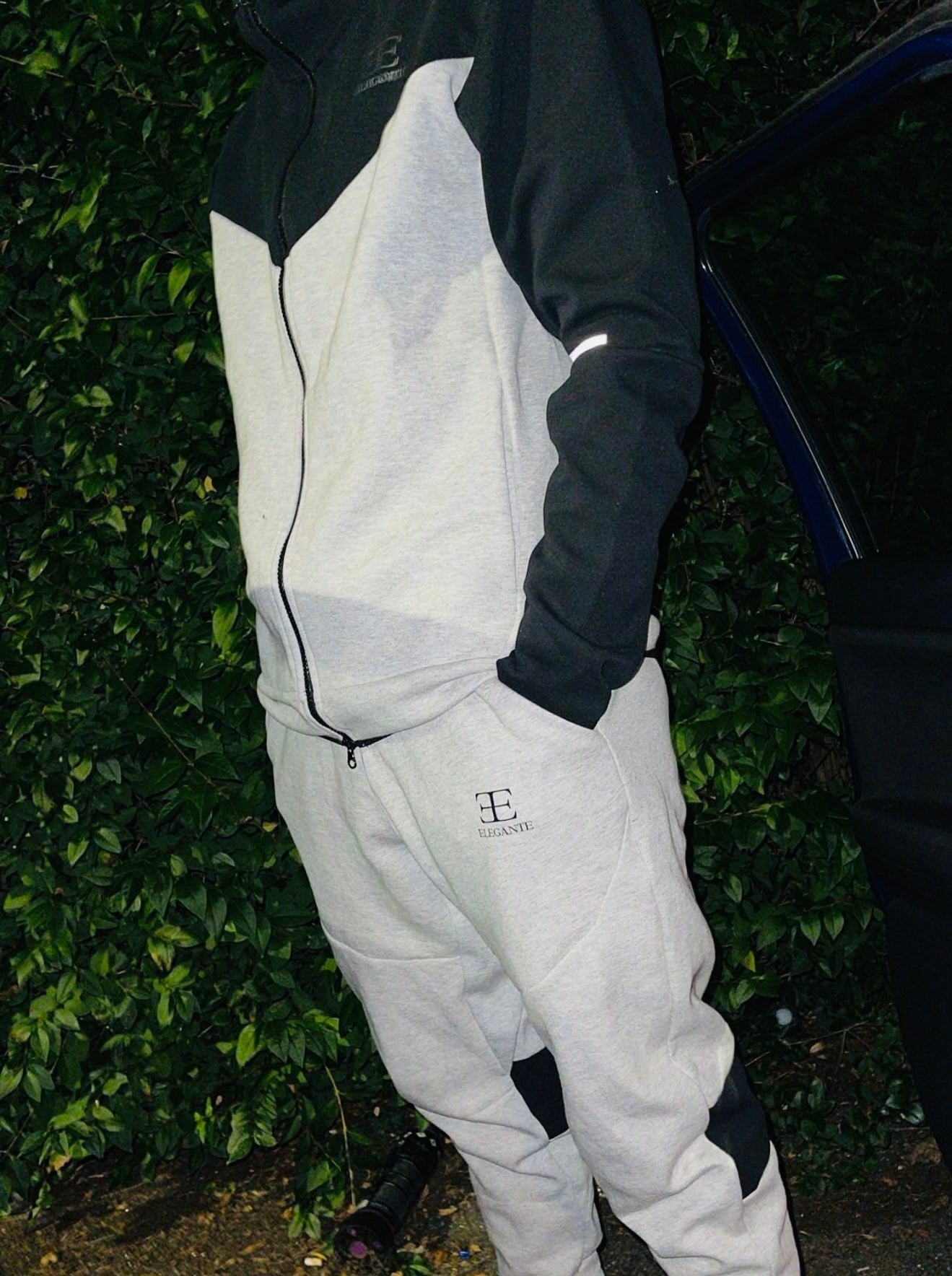 Man wearing a grey and black tracksuit with brand Elegante Clothing logo
