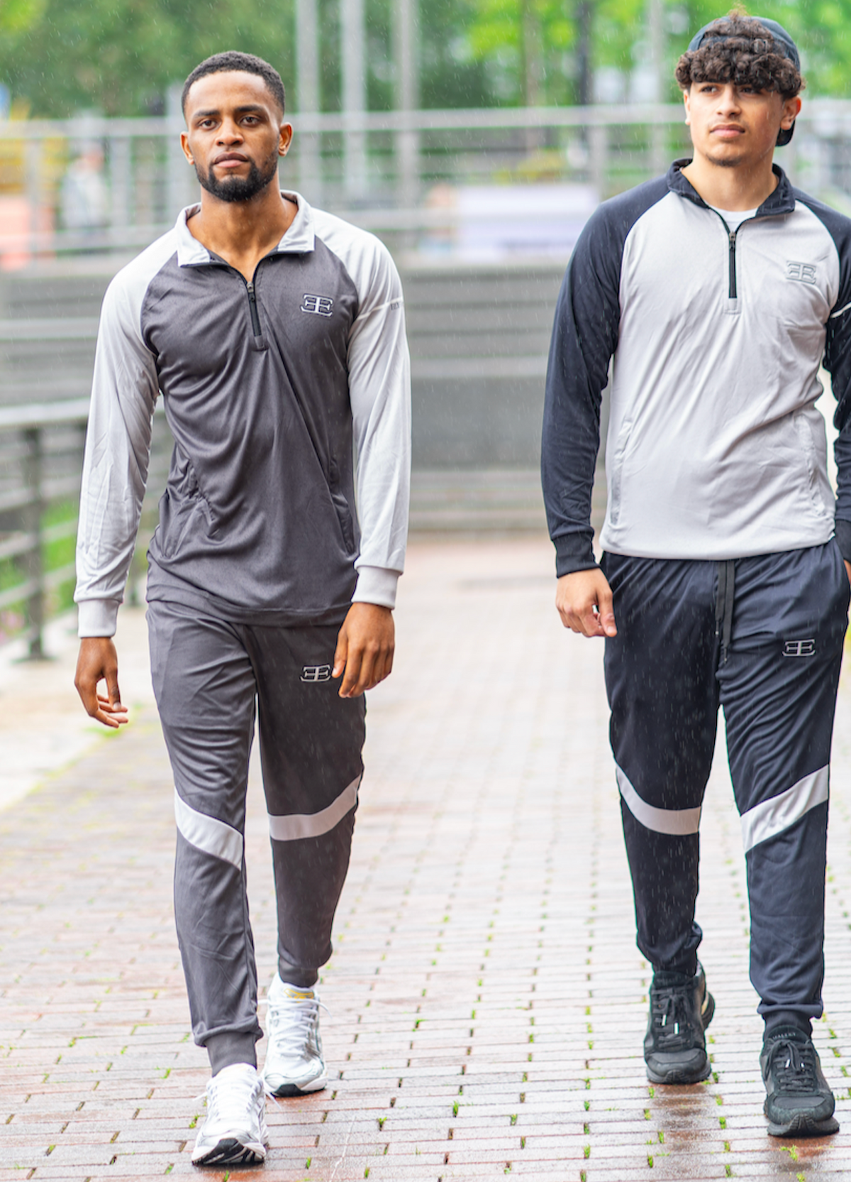 Two men wearing matching gray and black athletic outfits walking outdoors on a paved path.