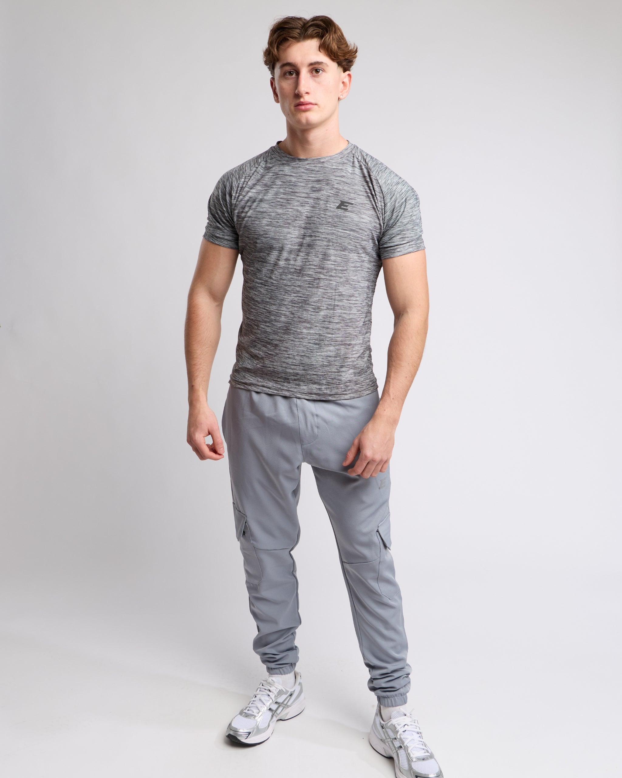 Man wearing a gray athletic tshirt and joggers with a elegante london logo on a light gray background