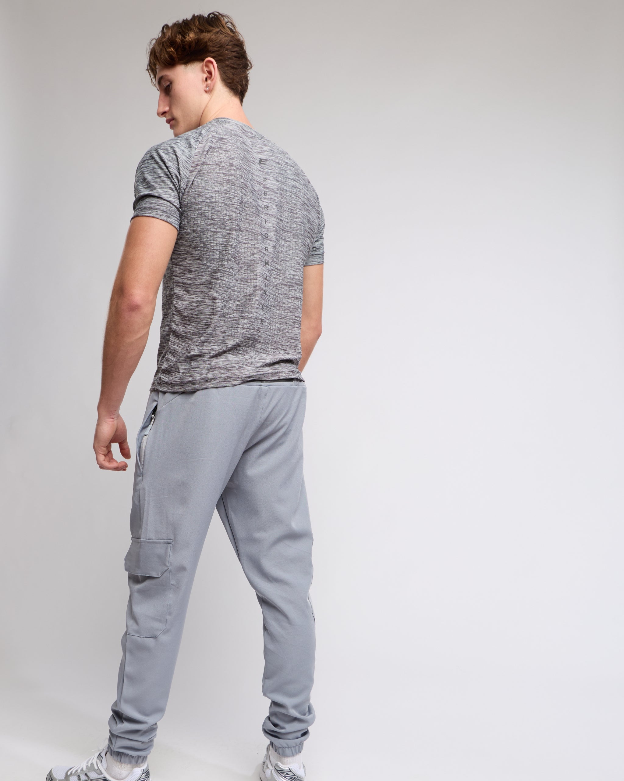 Man wearing a gray athletic tshirt and joggers with a elegante london logo on a light gray background