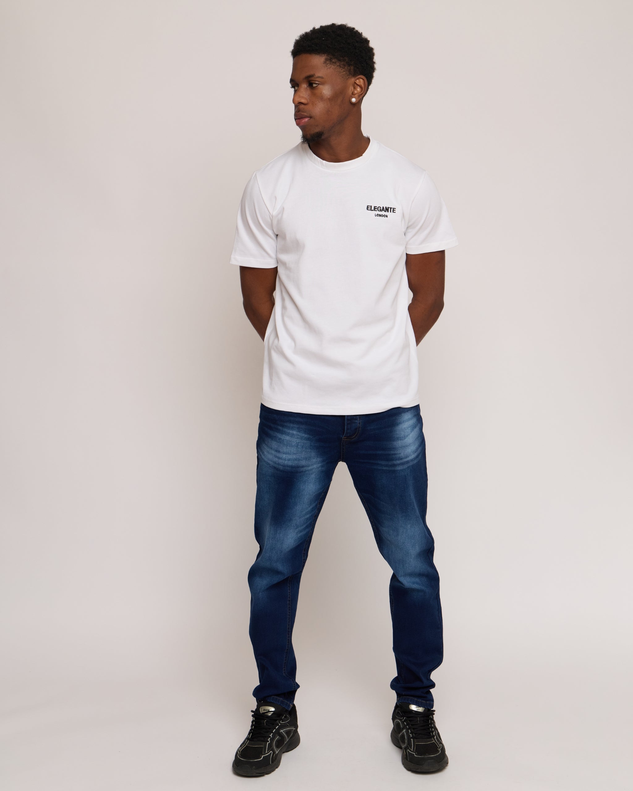 Man wearing a white cotton t-shirt with E logo and blue denim jeans