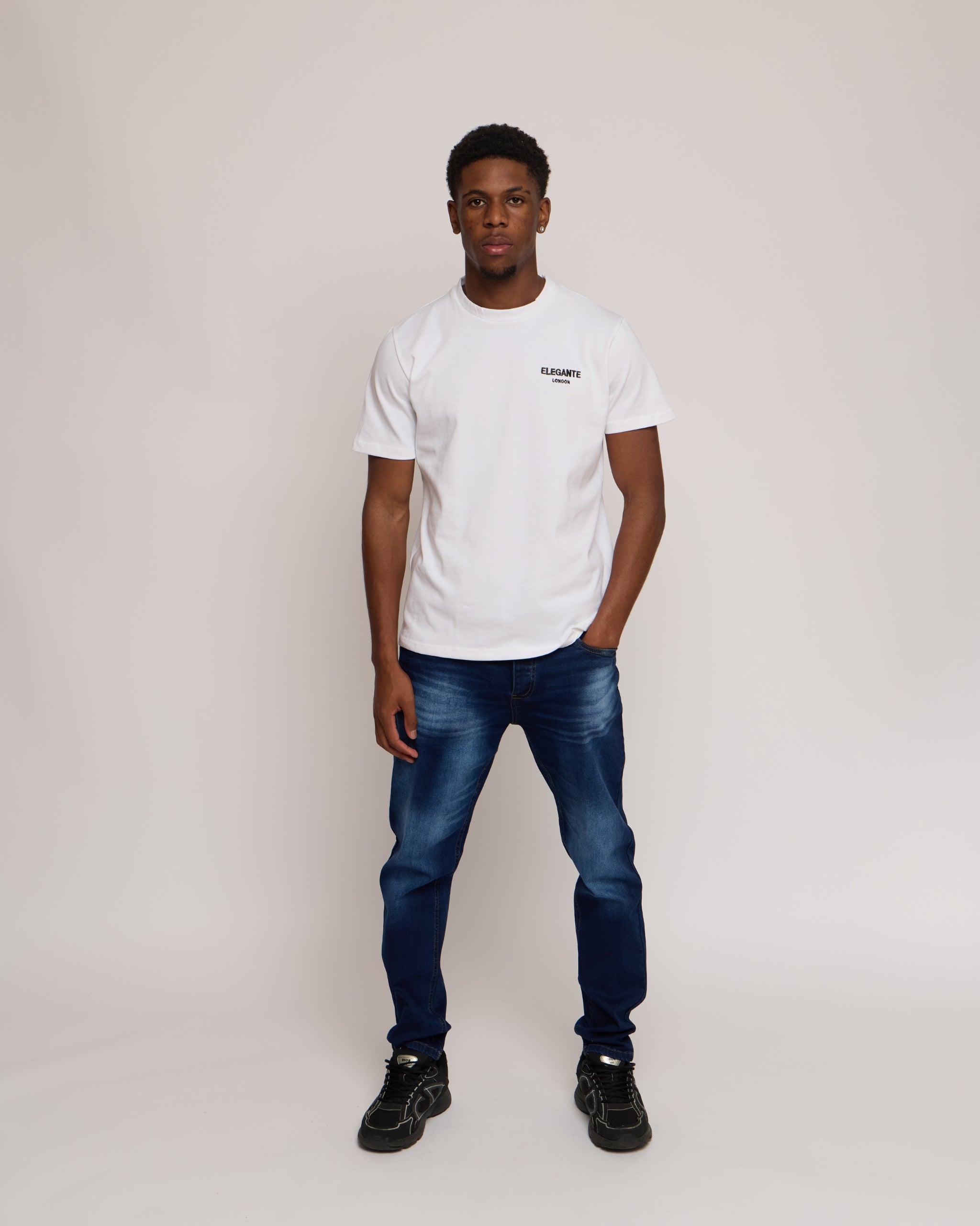 Man wearing a white cotton t-shirt with E logo and blue denim jeans