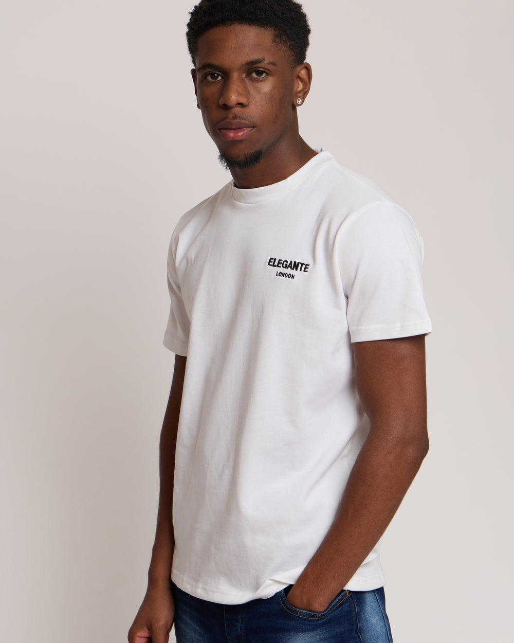 Man wearing a white cotton t-shirt with 'Elegante London' logo on a plain background