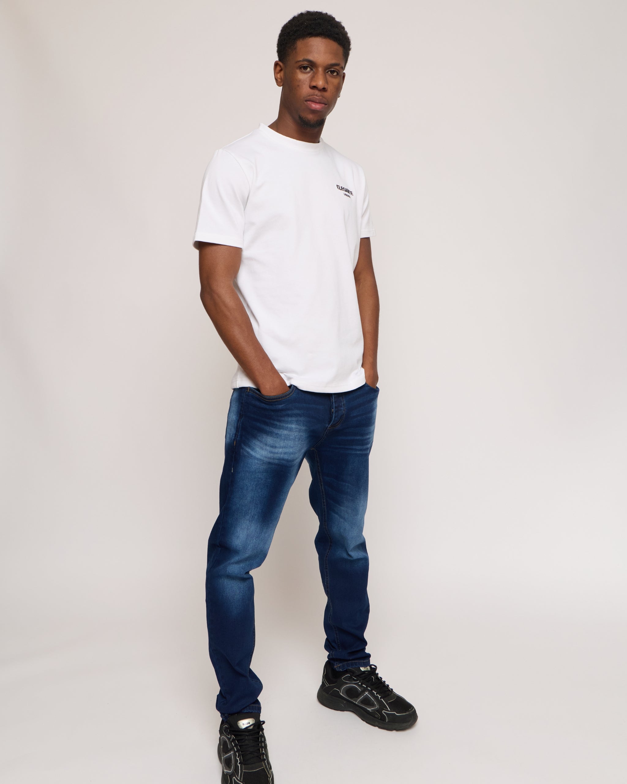 Man wearing a white cotton t-shirt with E logo and blue denim jeans