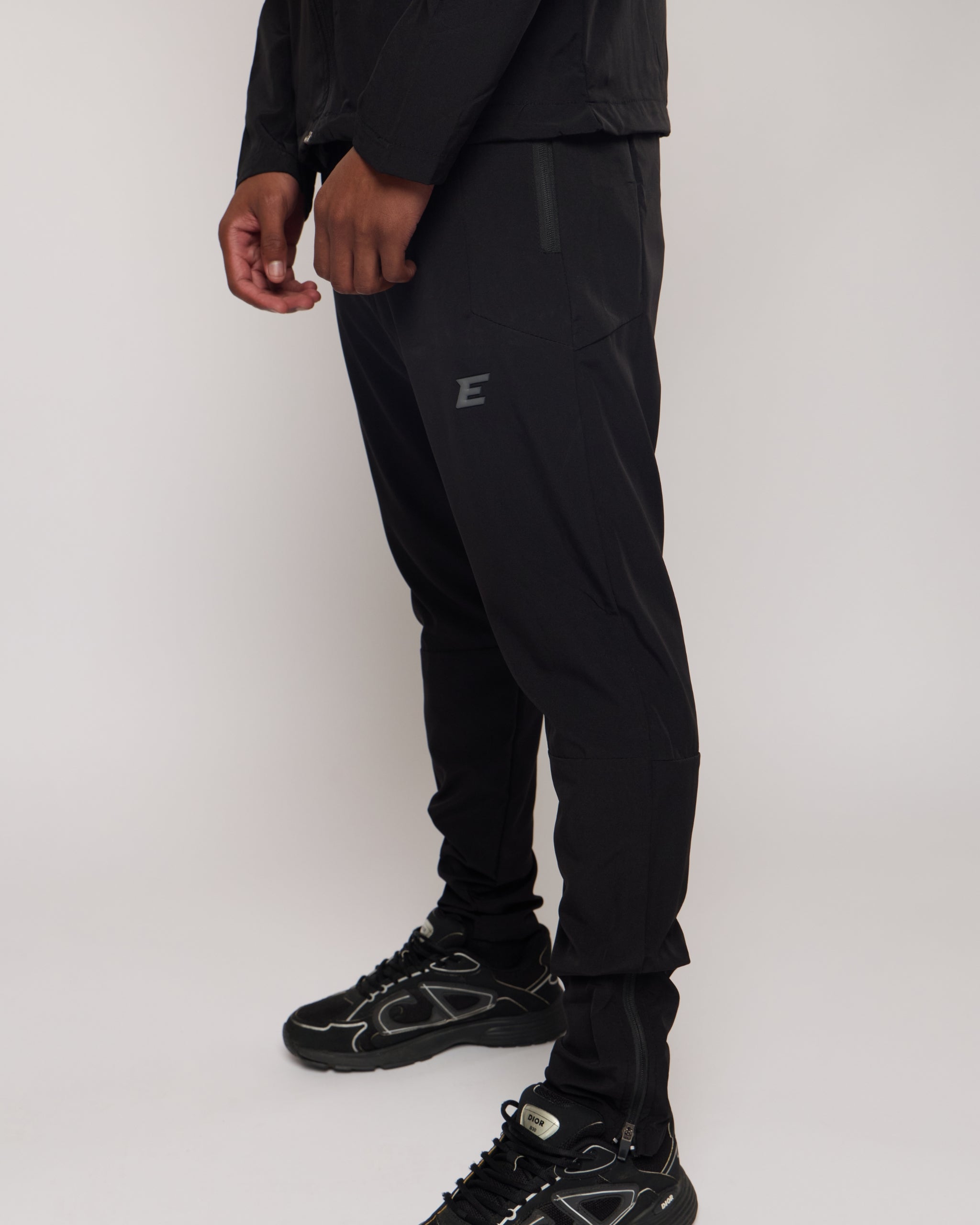 Person wearing black athletic pants with a E logo on a white background