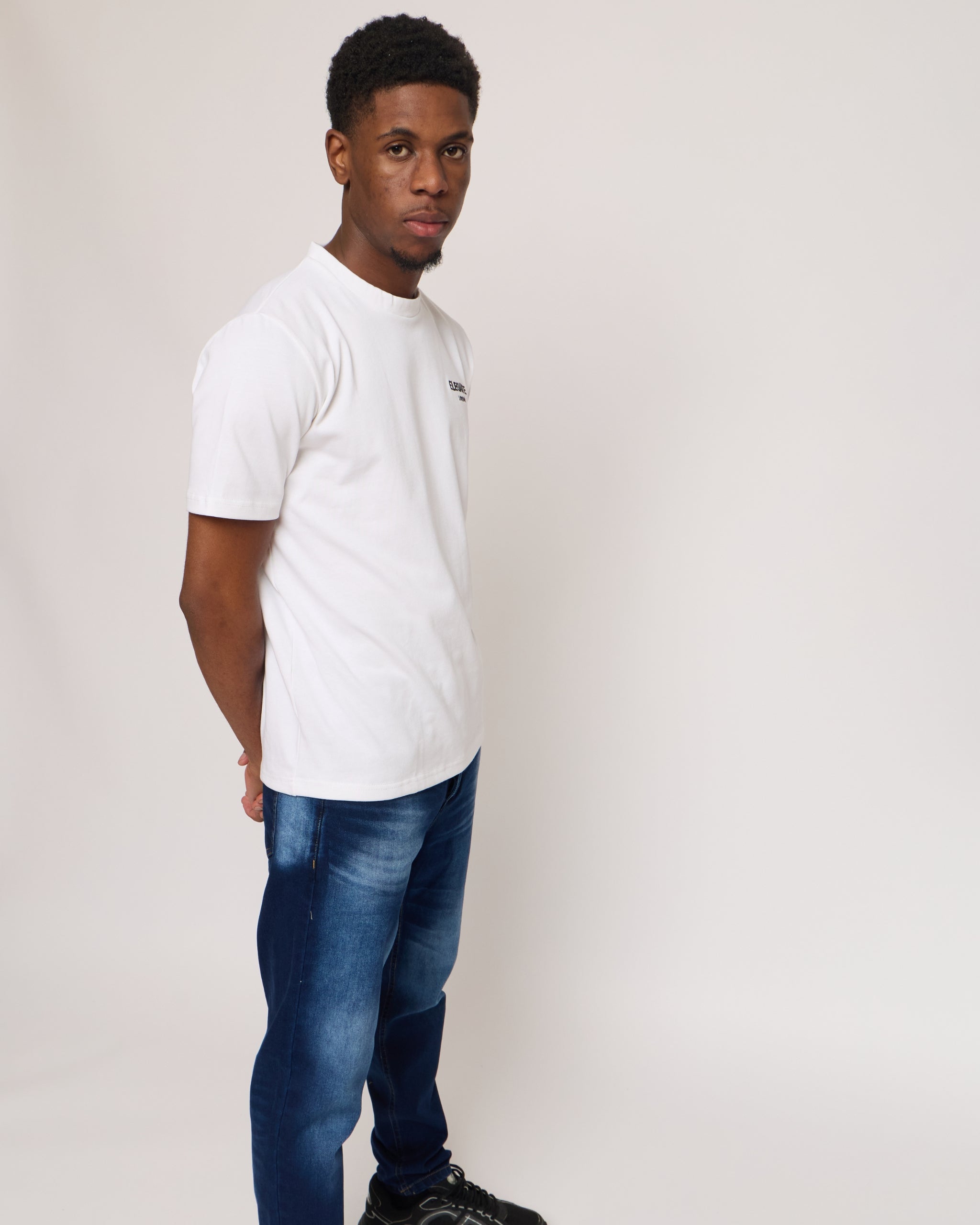 Man wearing a white cotton t-shirt with E logo and blue denim jeans