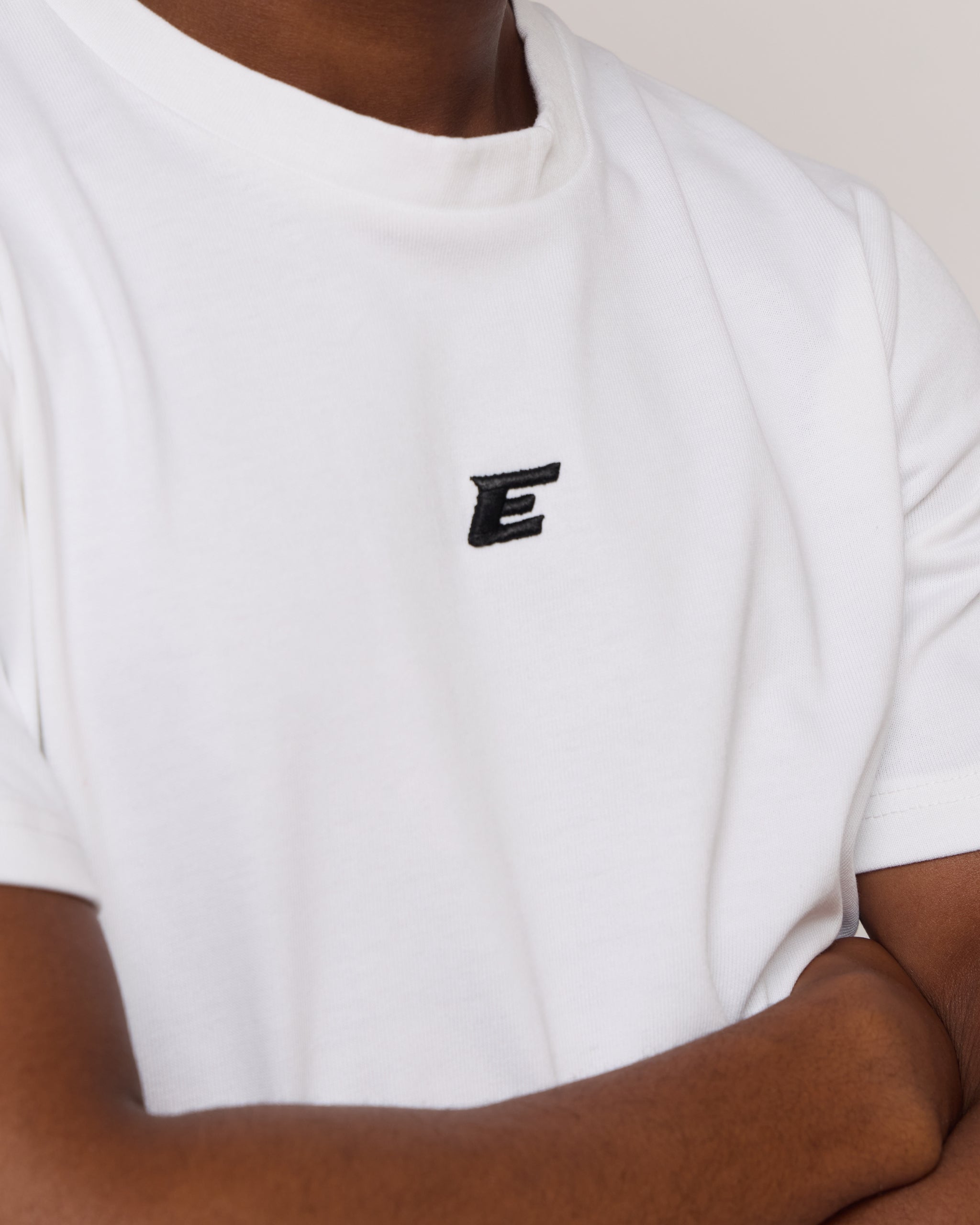 man wearing a white cotton t-shirt with black 'E' Logo 