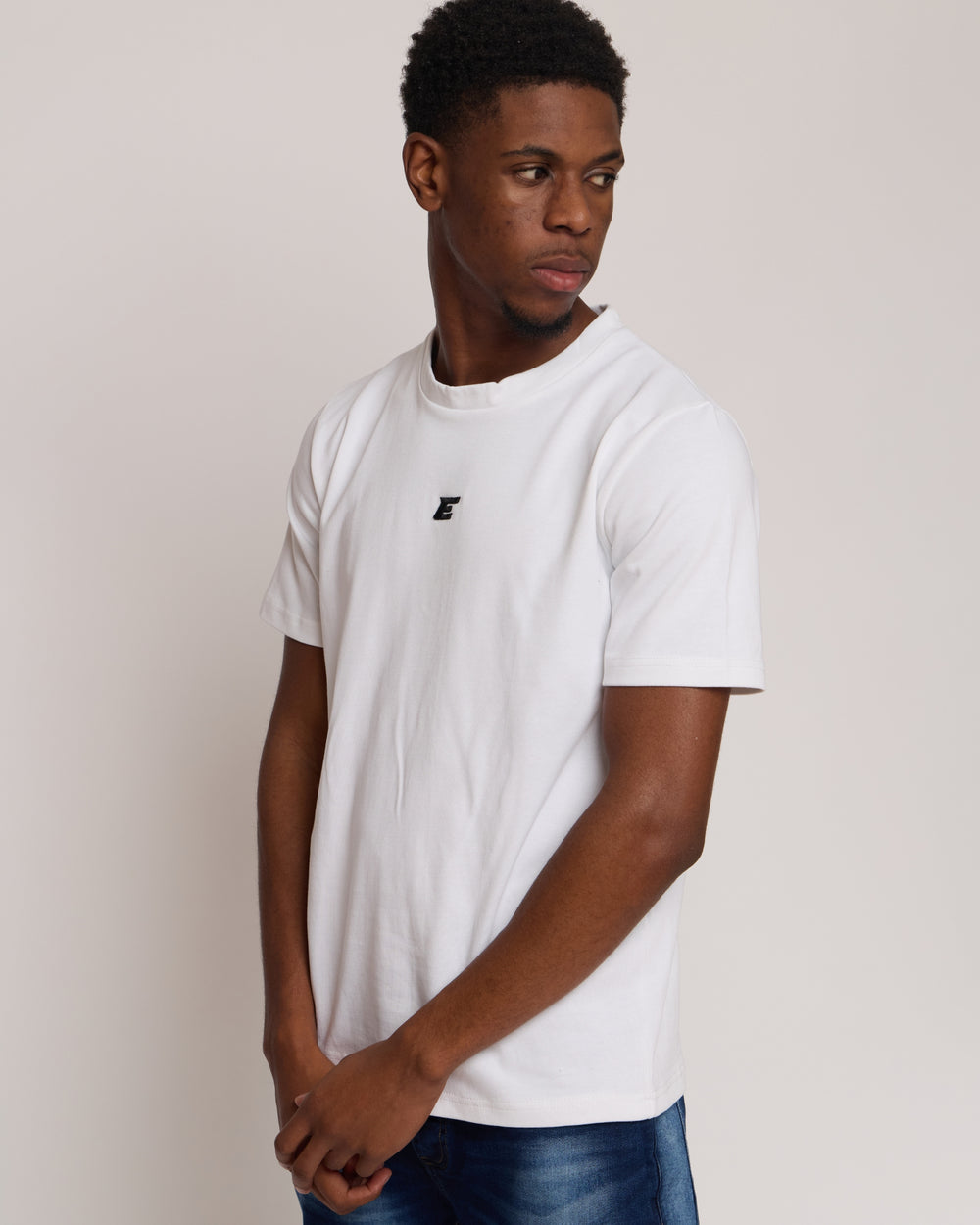 man wearing a white cotton t-shirt with 'E' Logo and blue denim jeans on a white background