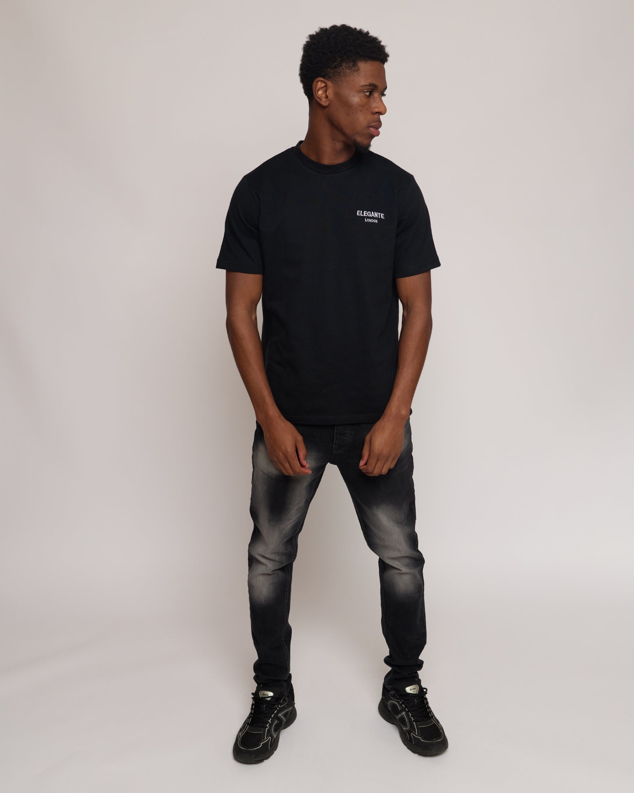 man wearing a black cotton t-shirt and jeans on a white background