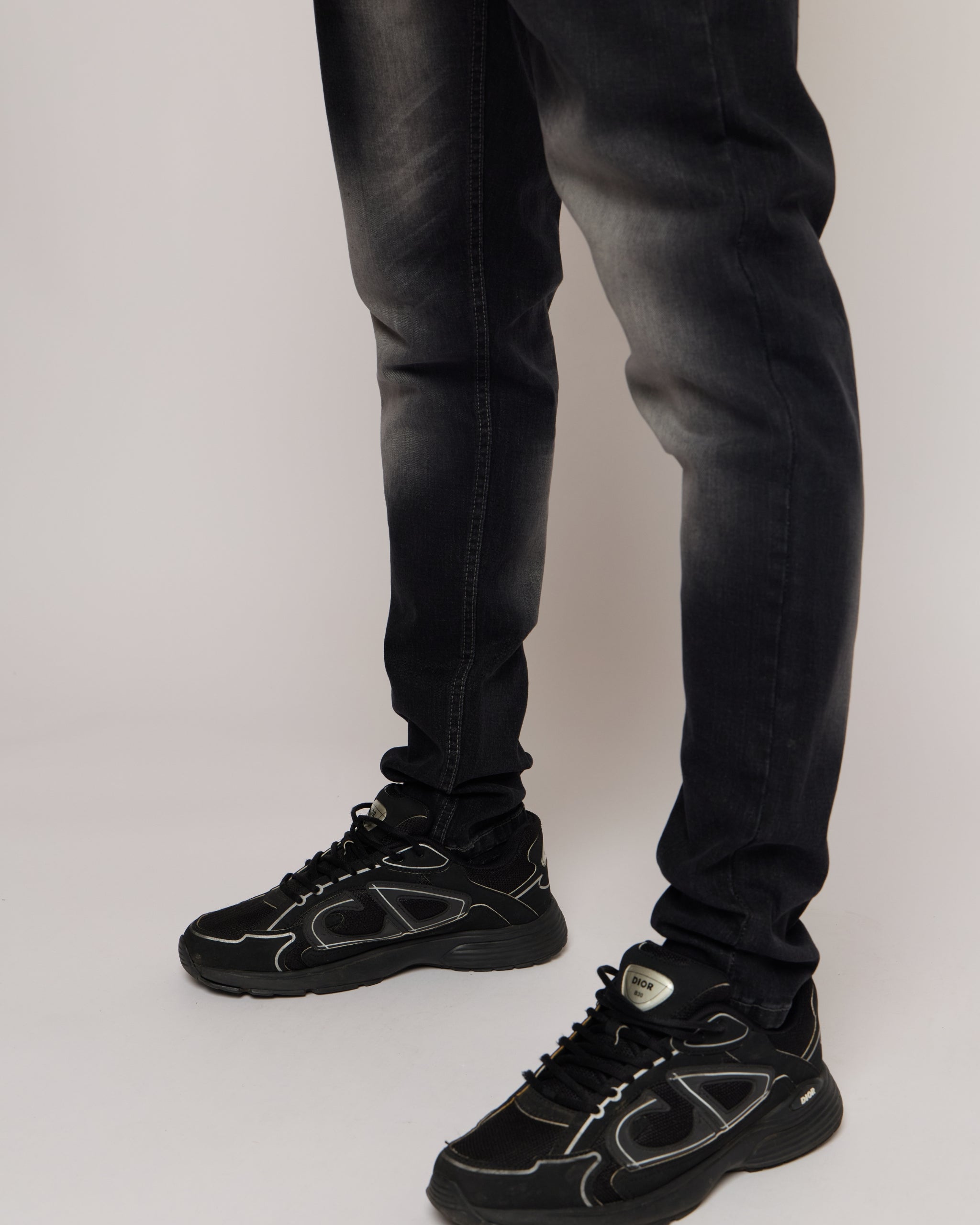 Black jeans and black sneakers on a plain background