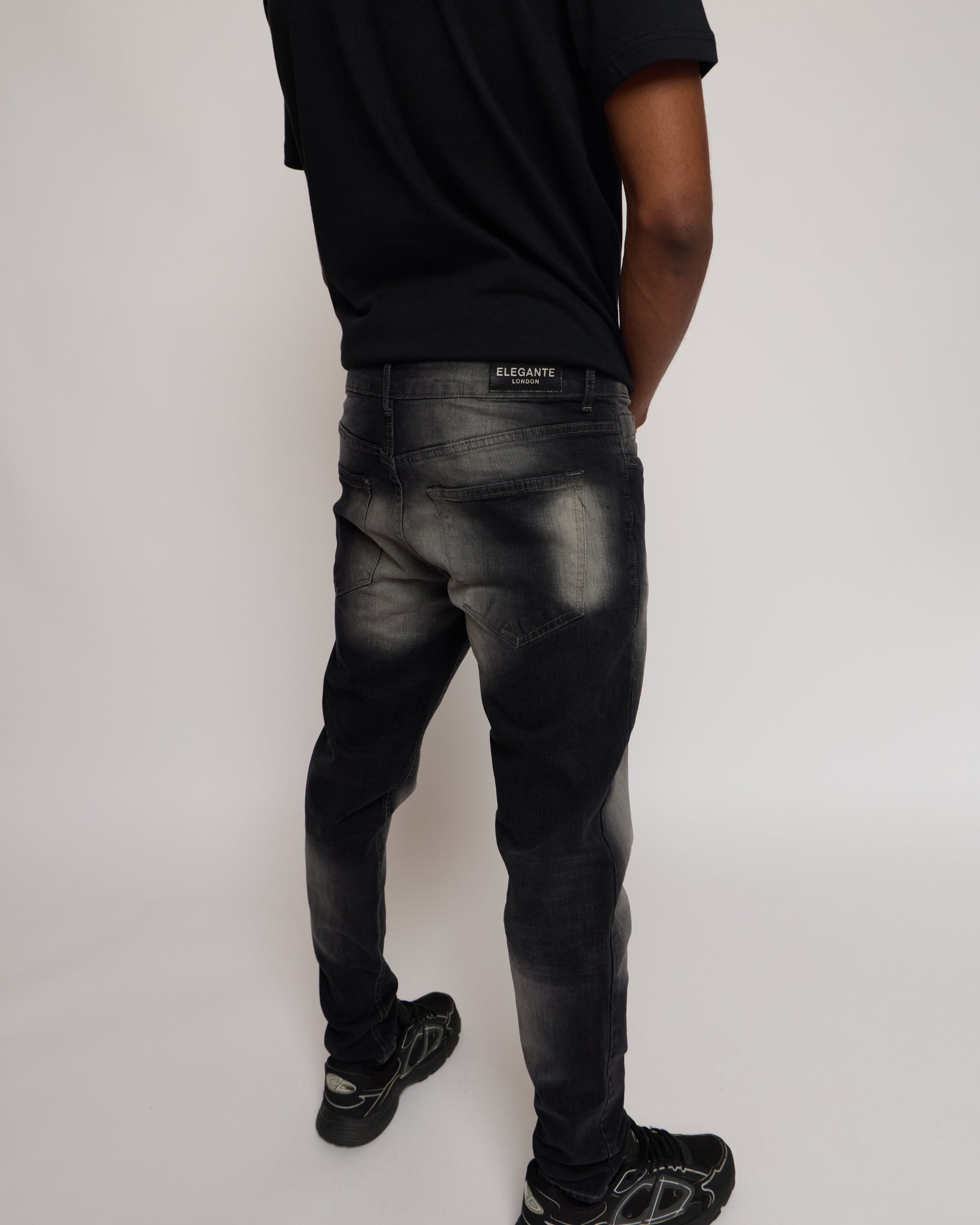 Person wearing black distressed jeans and a black shirt on a white background