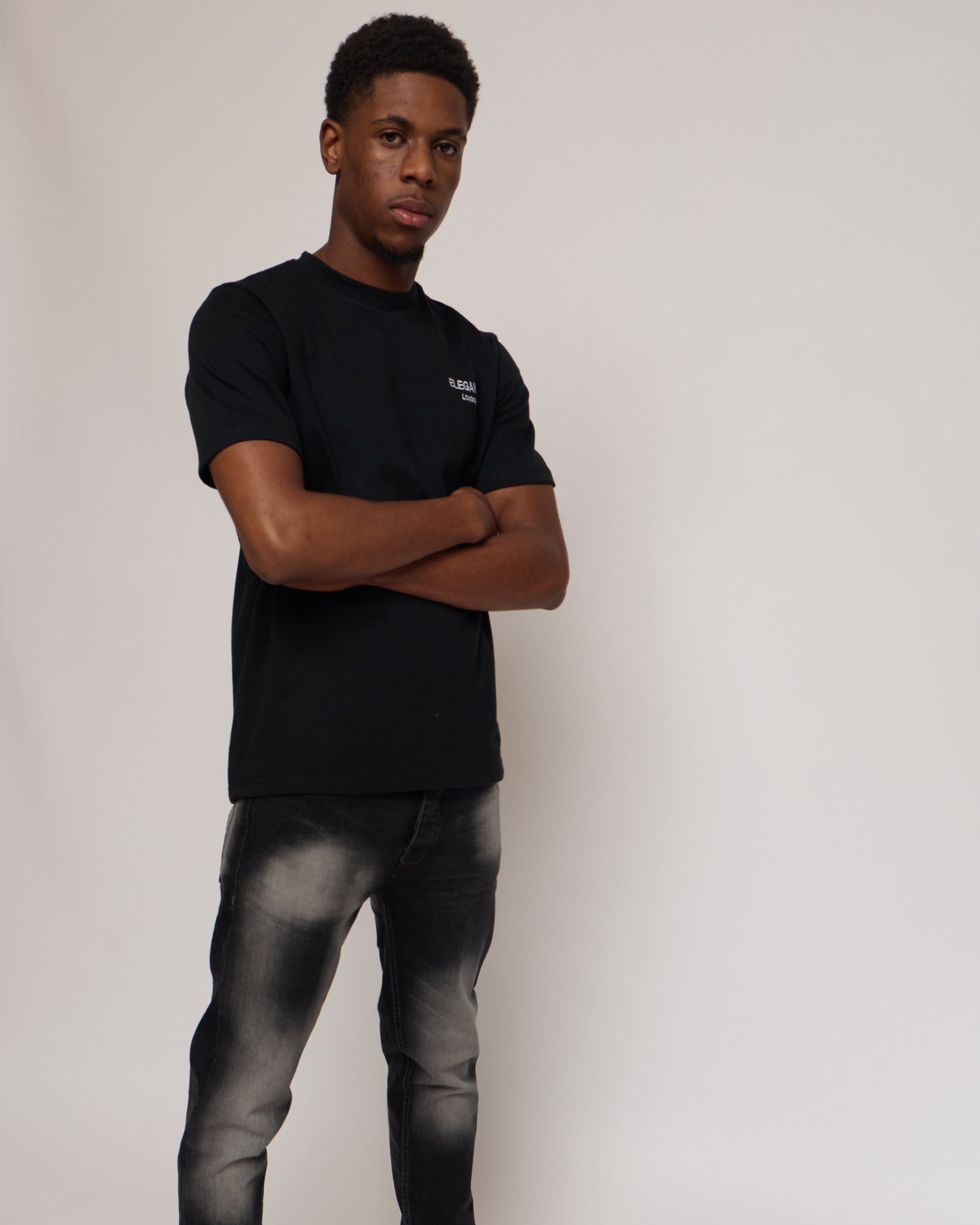 man wearing a black cotton t-shirt and jeans on a white background