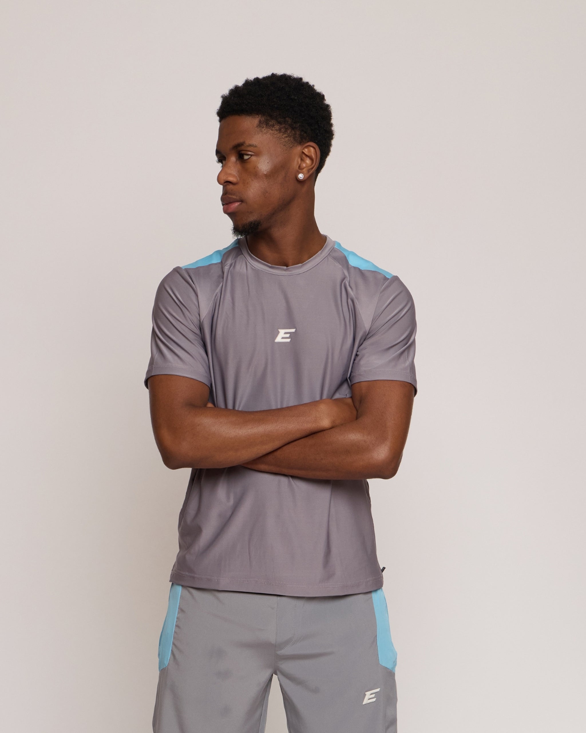 man wearing a dark gray athletic t-shirt with blue accents with an elegante logo on a plain background