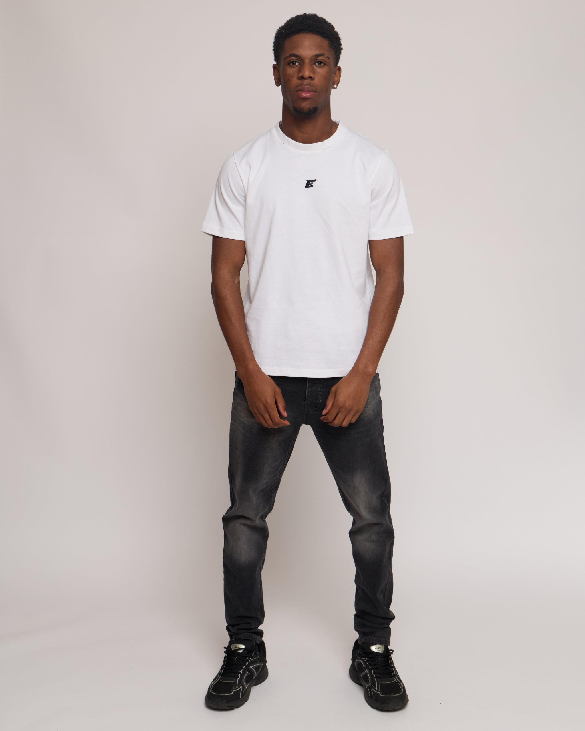 Man wearing a white cotton t-shirt with E logo and grey denim jeans