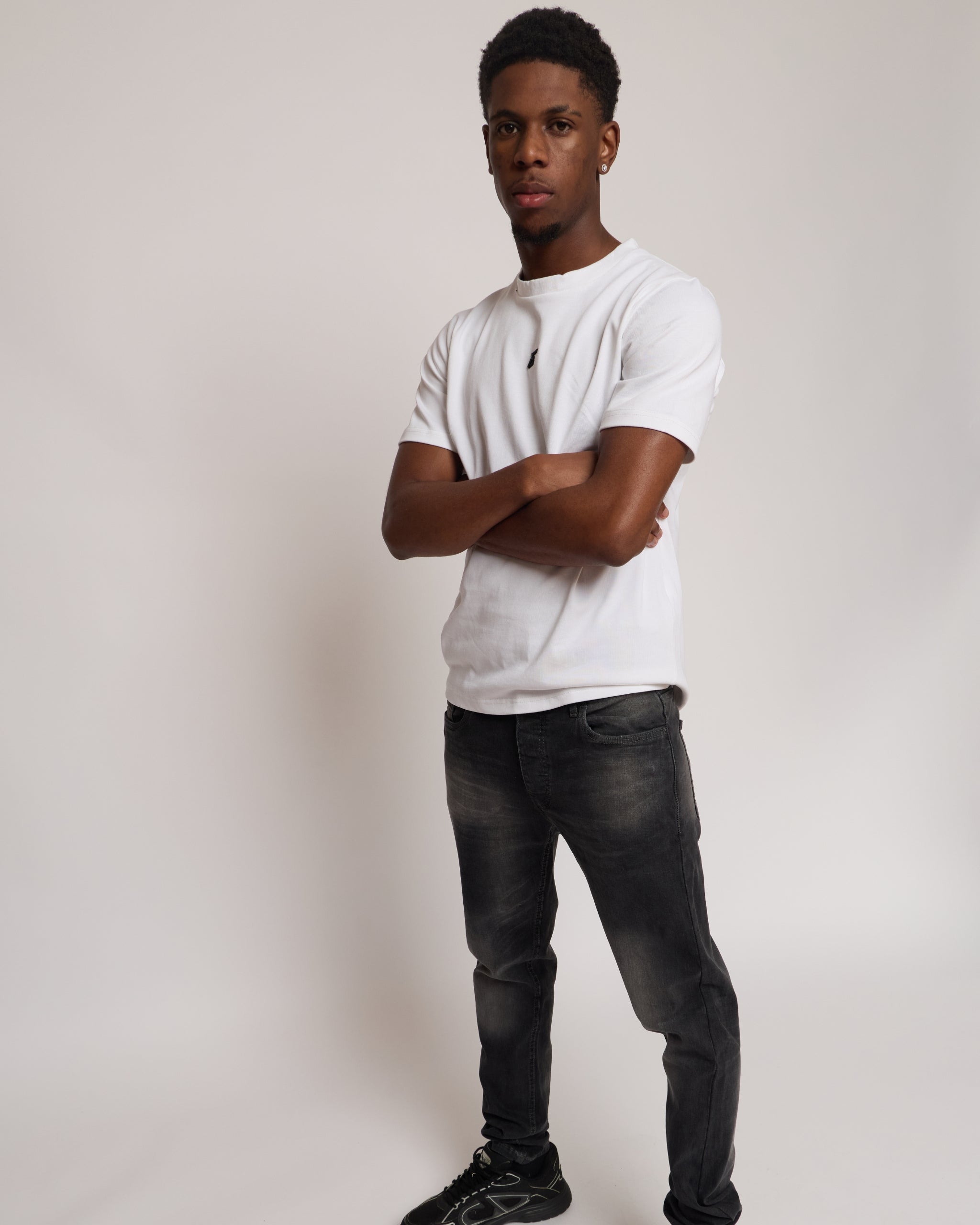 Man wearing a white cotton t-shirt with E logo and grey denim jeans