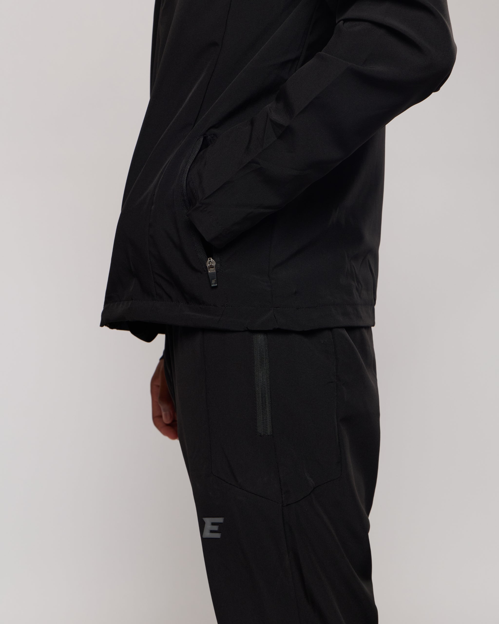 Person wearing a black jacket and pants on a plain background