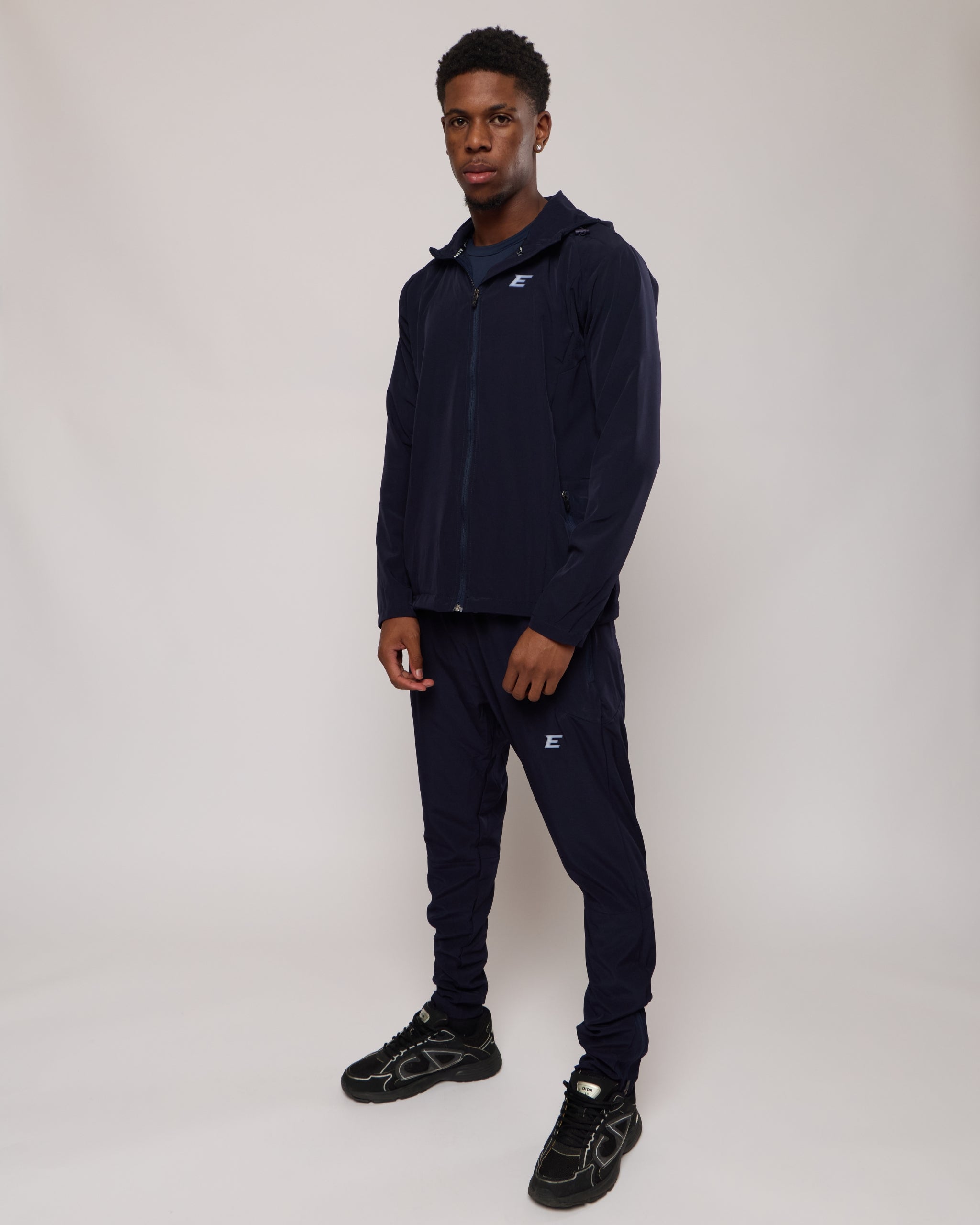man wearing a full navy tracksuit set with 'Elegante' branding on a white background