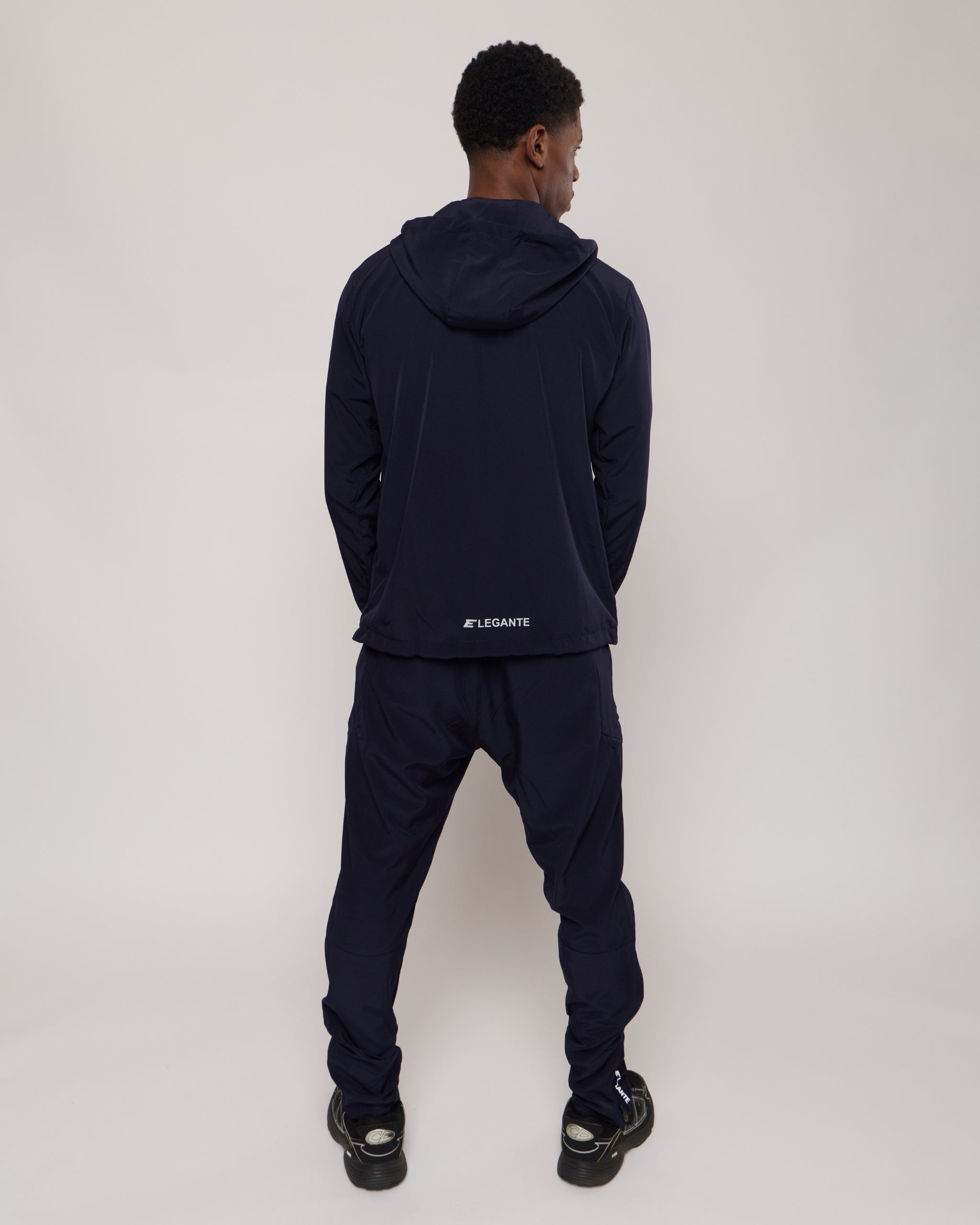 man wearing a full navy tracksuit set with 'Elegante' branding on a white background