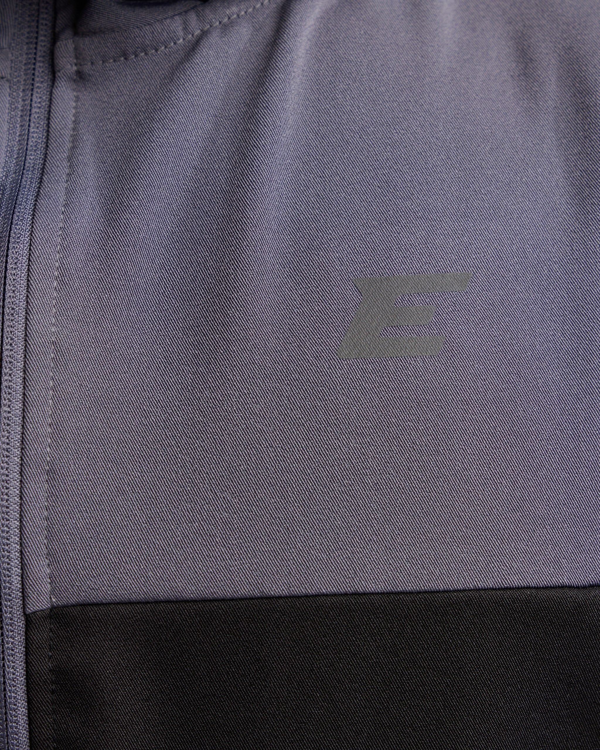Close-up of a gray jacket with a brand logo on the chest.