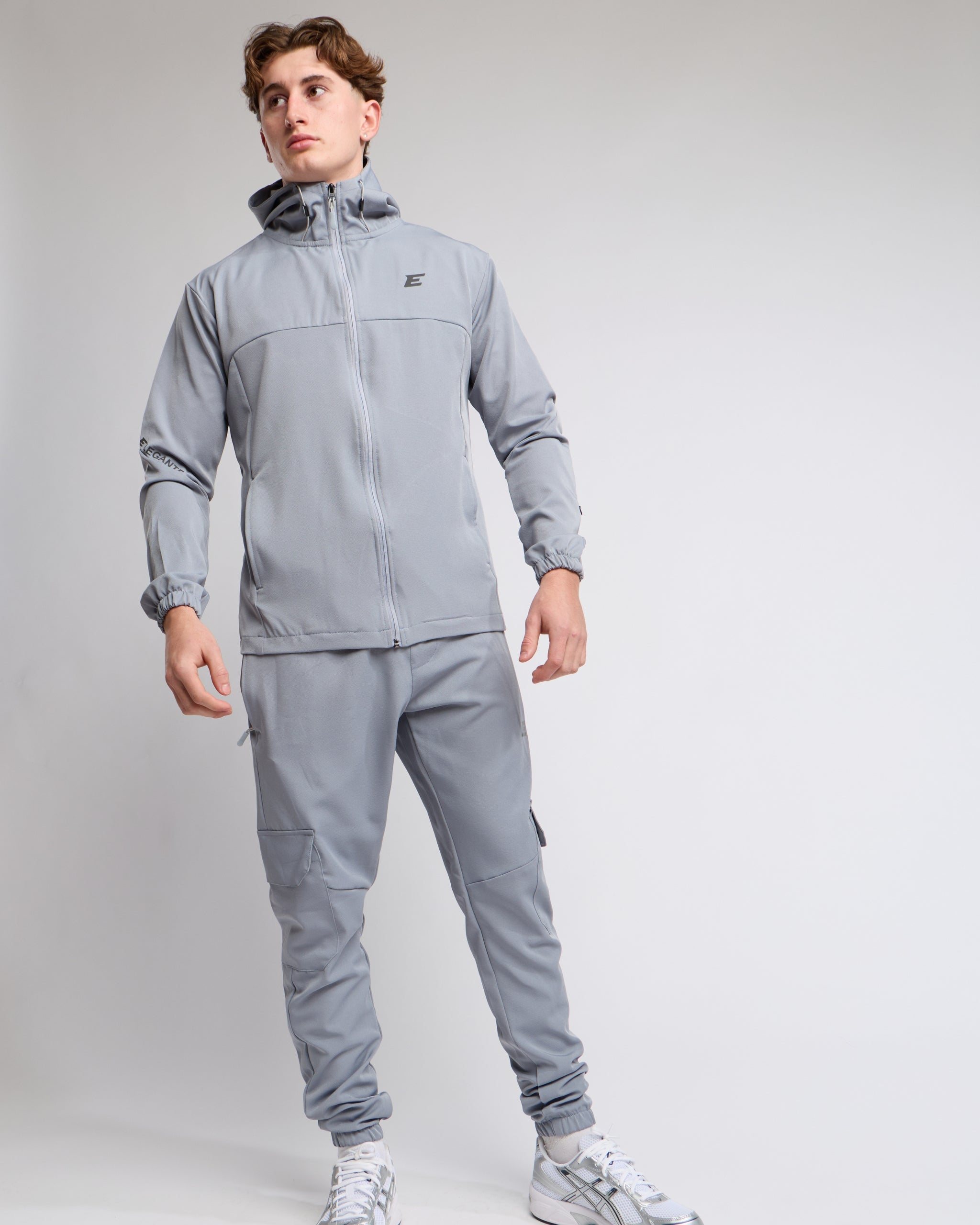 Man wearing a light gray tracksuit set on a light gray background
