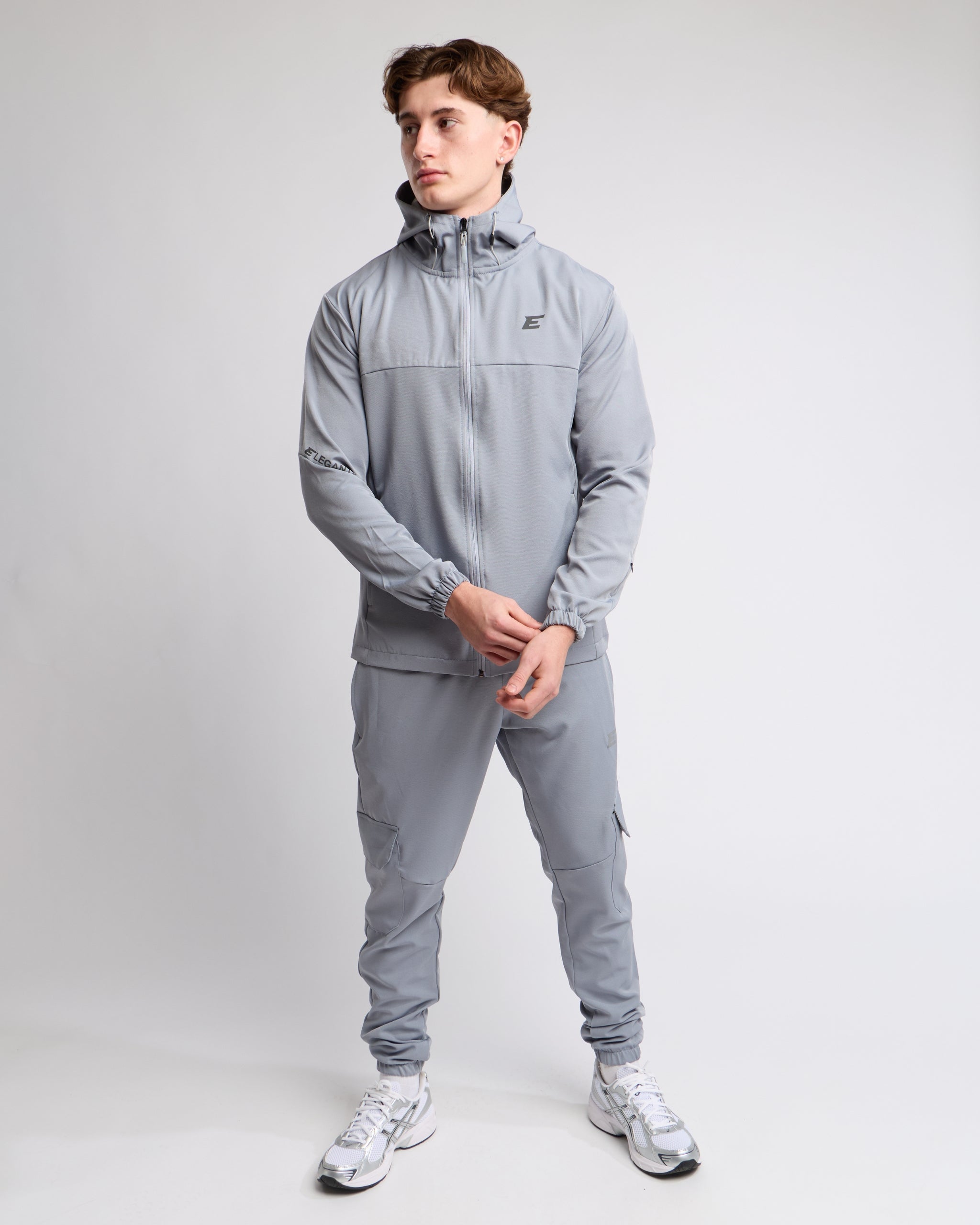 Man wearing a light gray tracksuit set on a light gray background