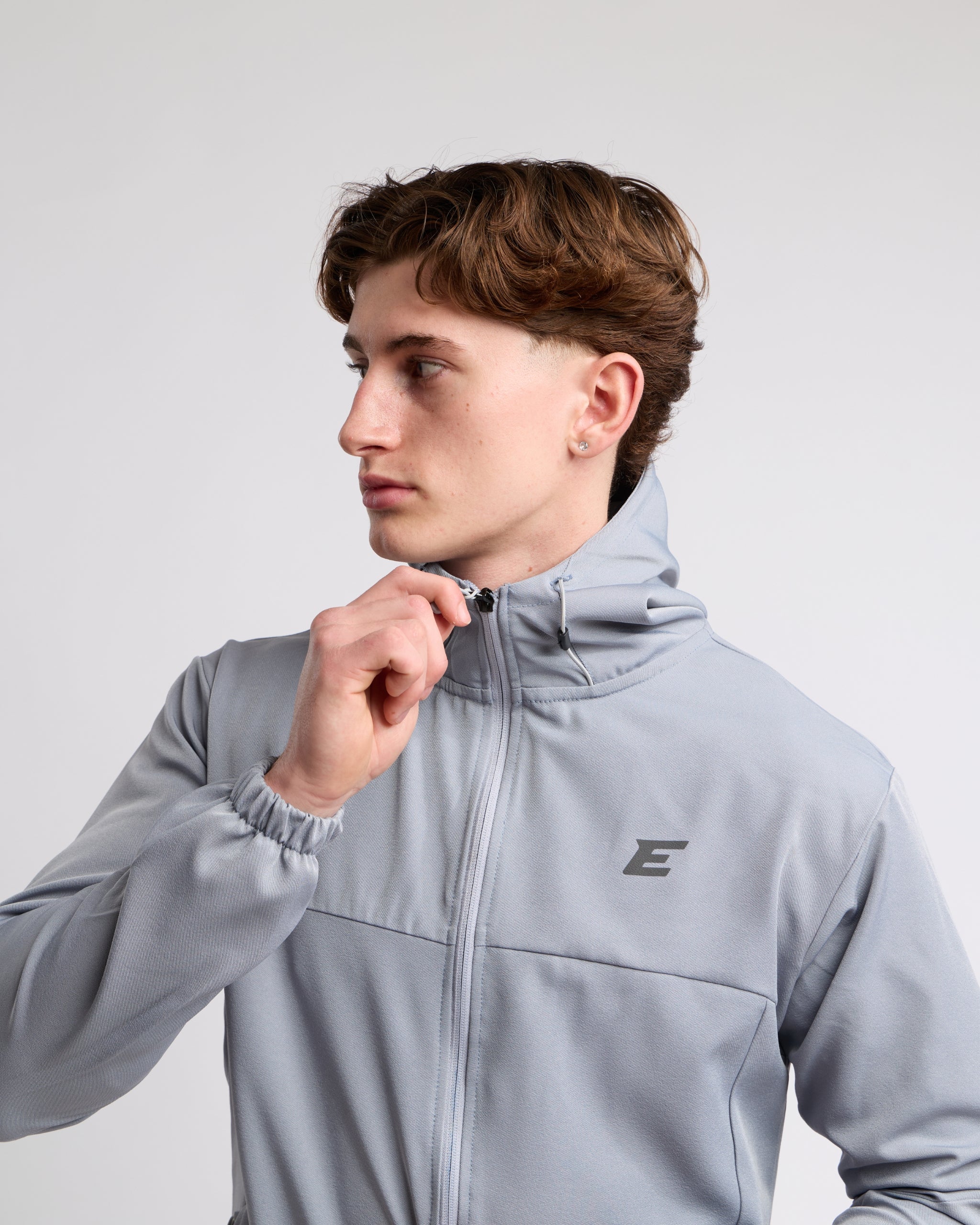 Man wearing a gray jacket with hood and  elegante brand logo on a light gray background