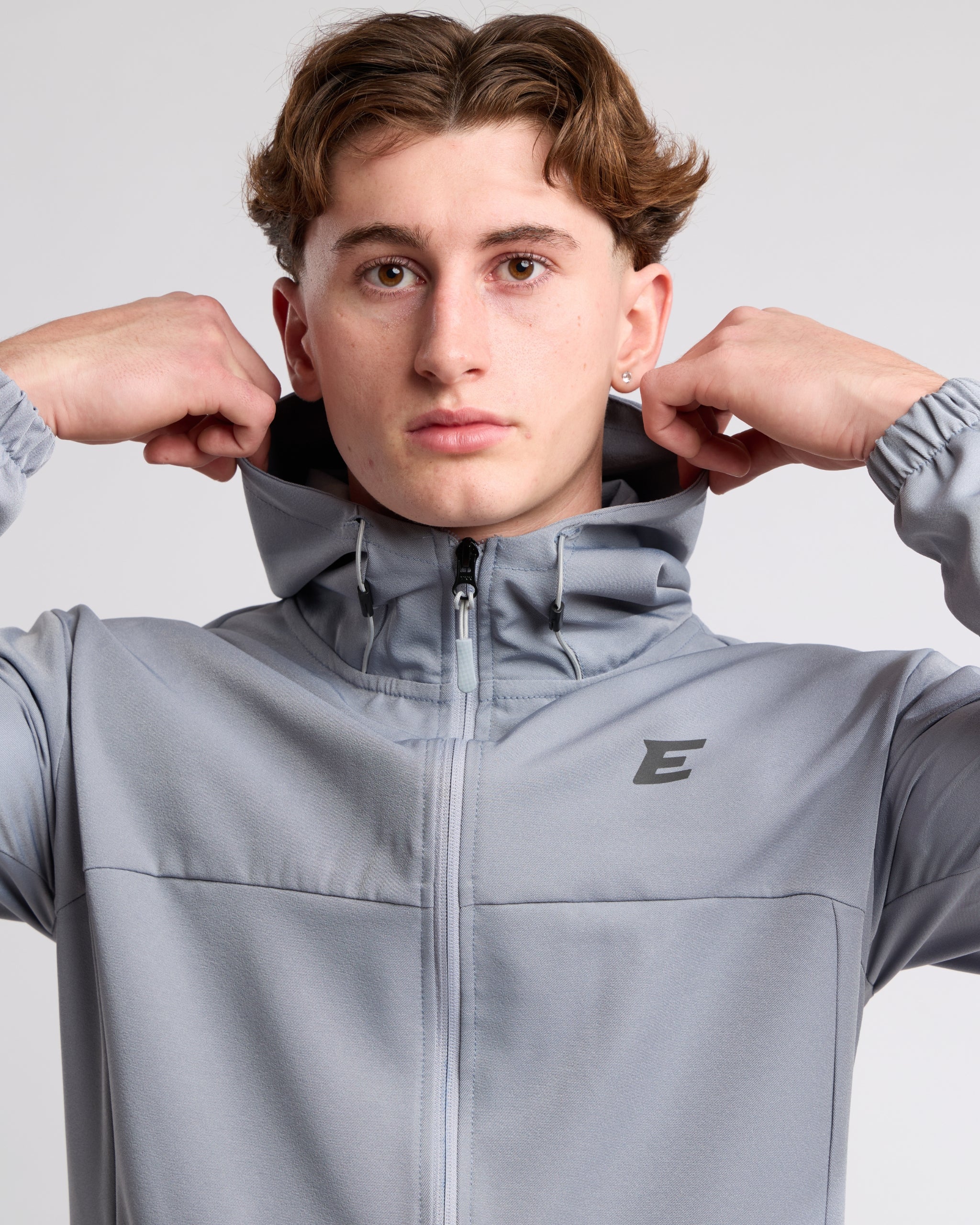 Man wearing a gray jacket with elegante brand logo on a light gray background