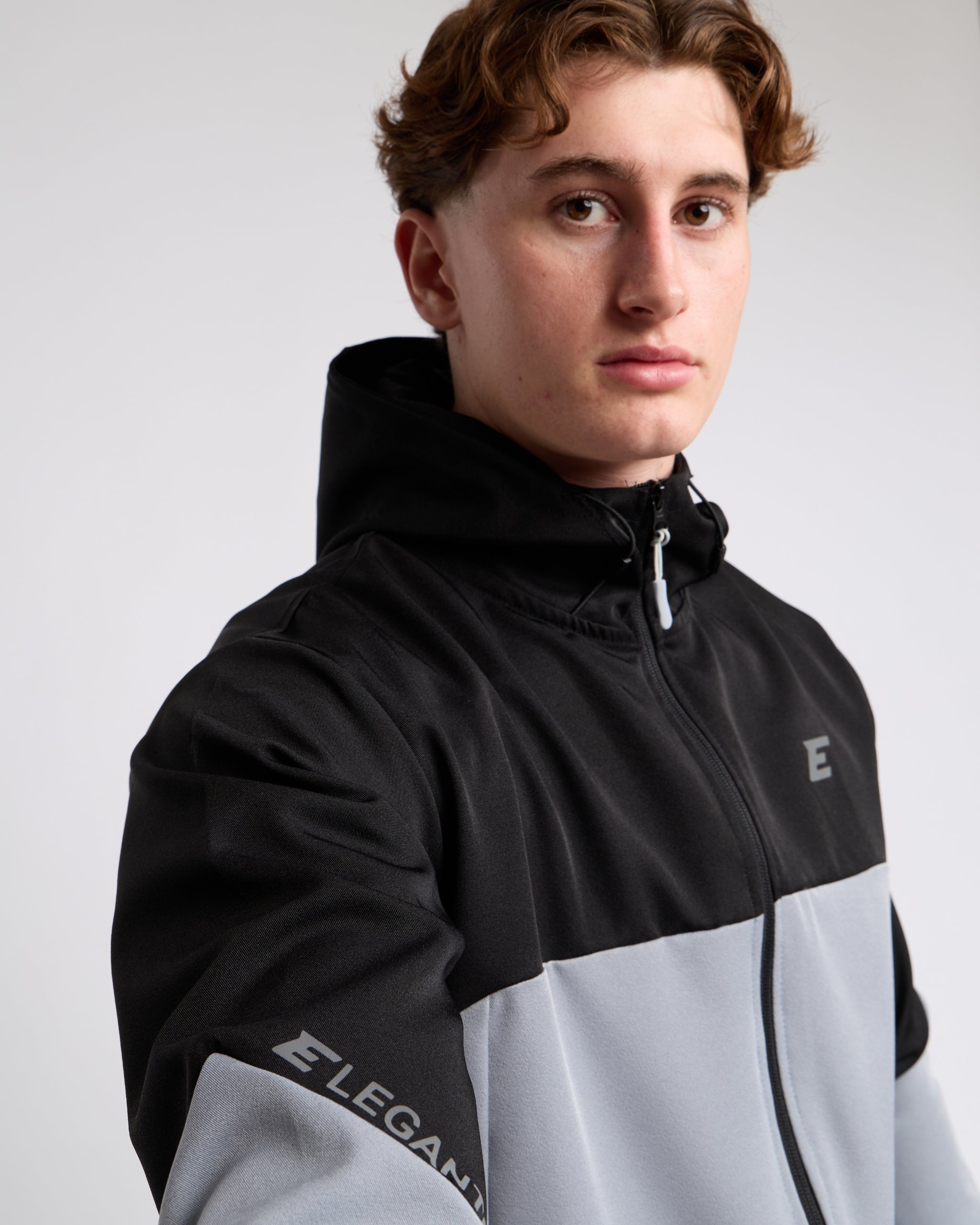 man wearing a black and gray jacket with elegante brand logo on a white background