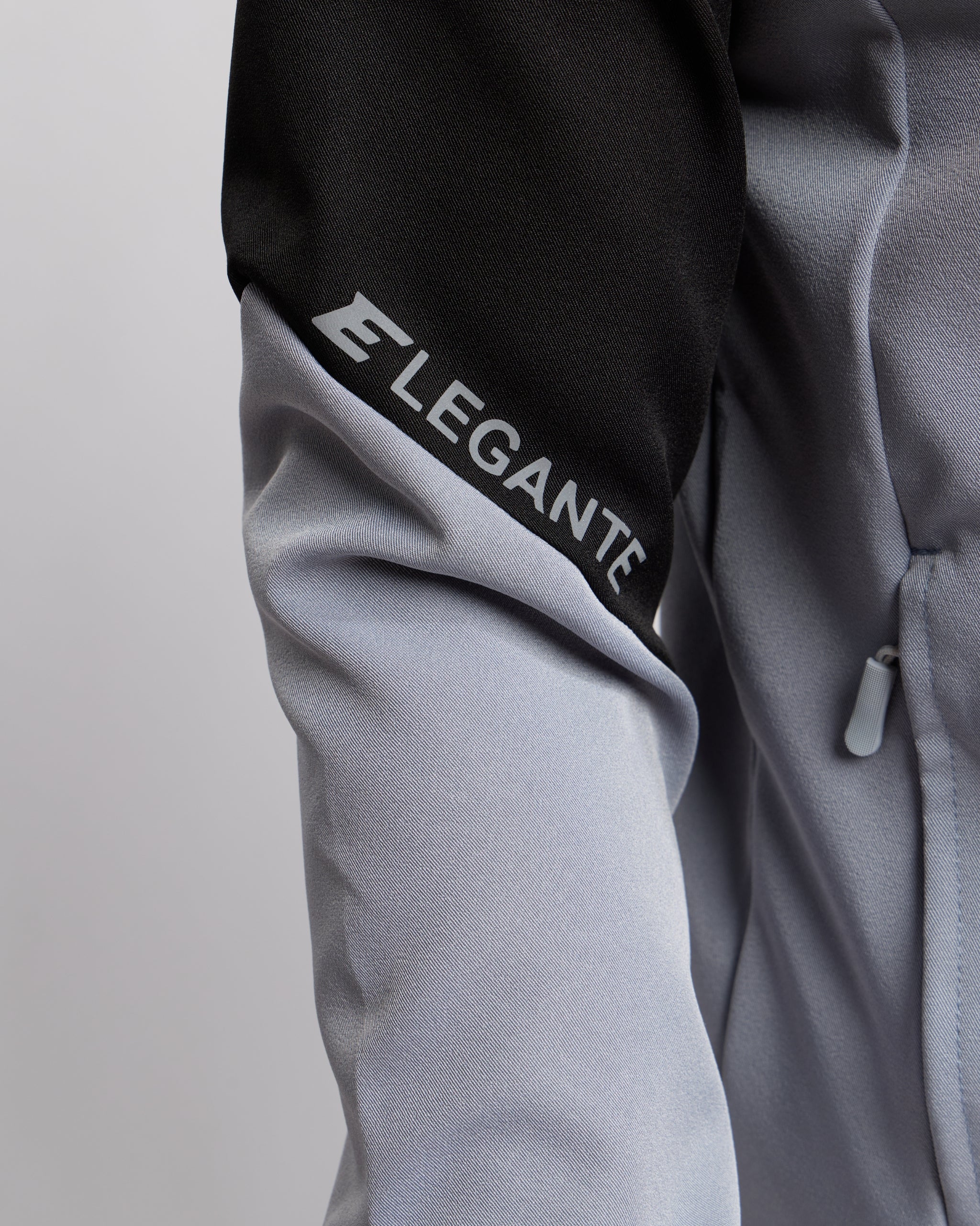 Gray jacket with 'ELEGANTE' branding on sleeve against a light gray background