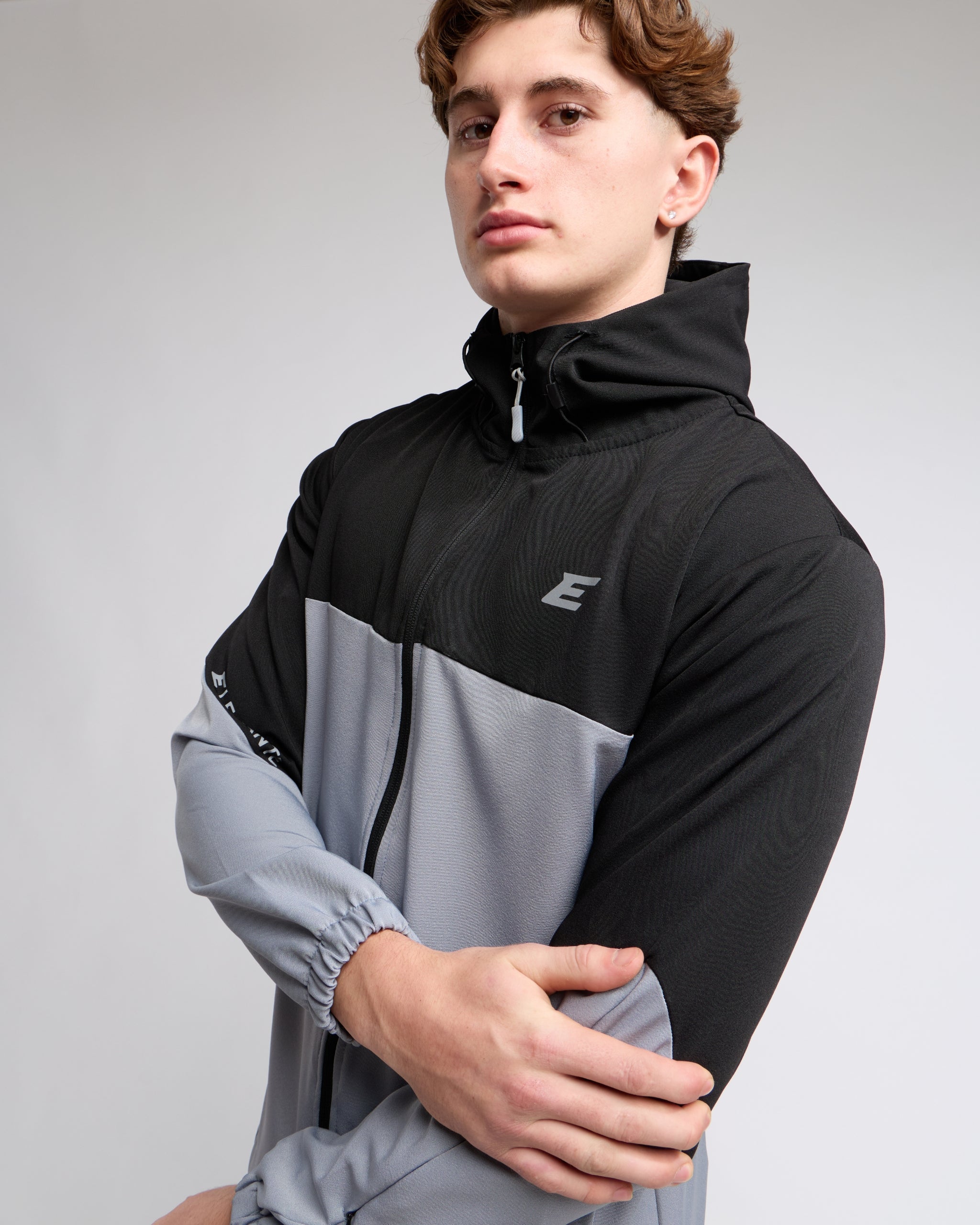 man wearing a black and gray tracksuit with a elegante brand logo on a light gray background