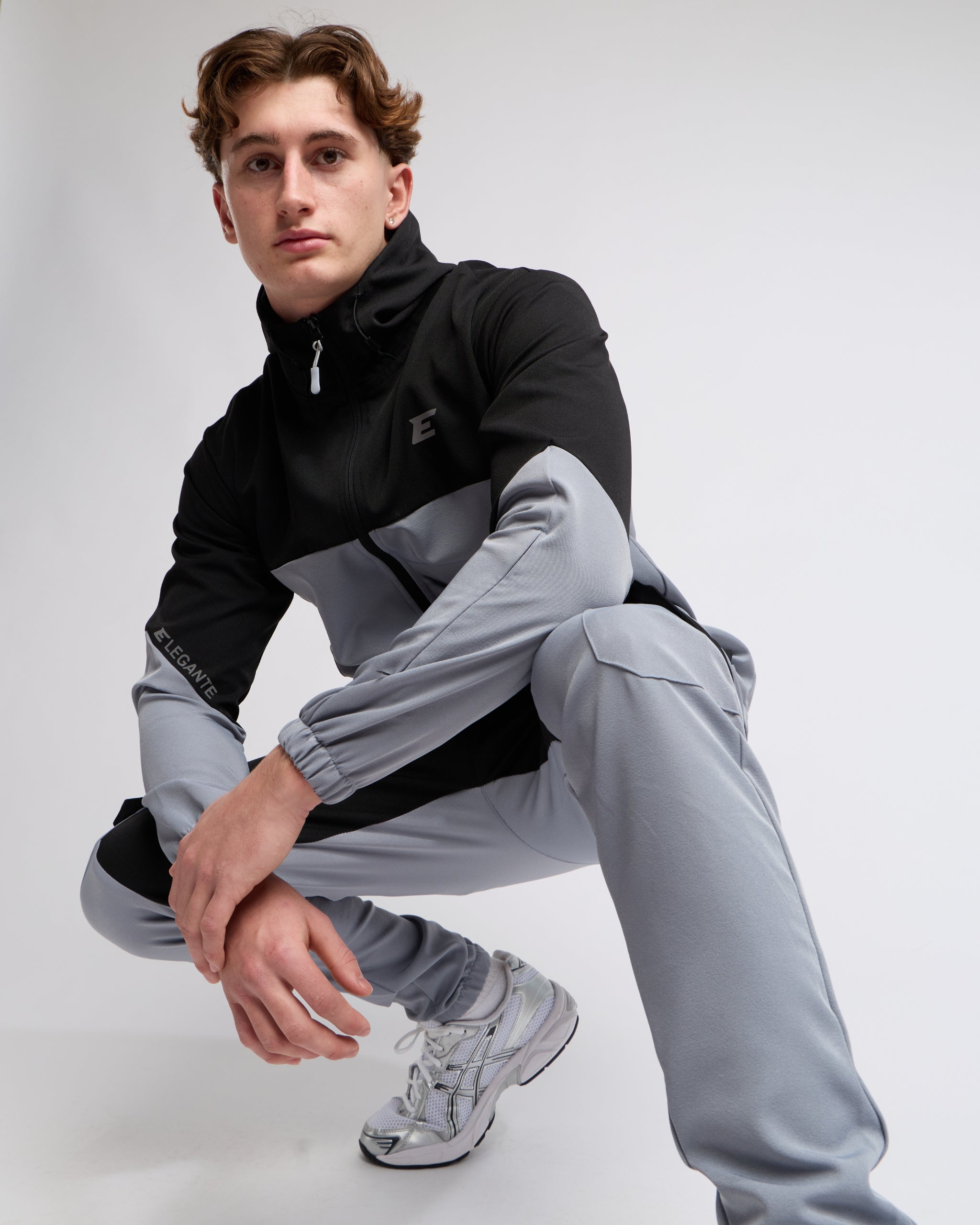 man wearing a black and gray tracksuit on a white background