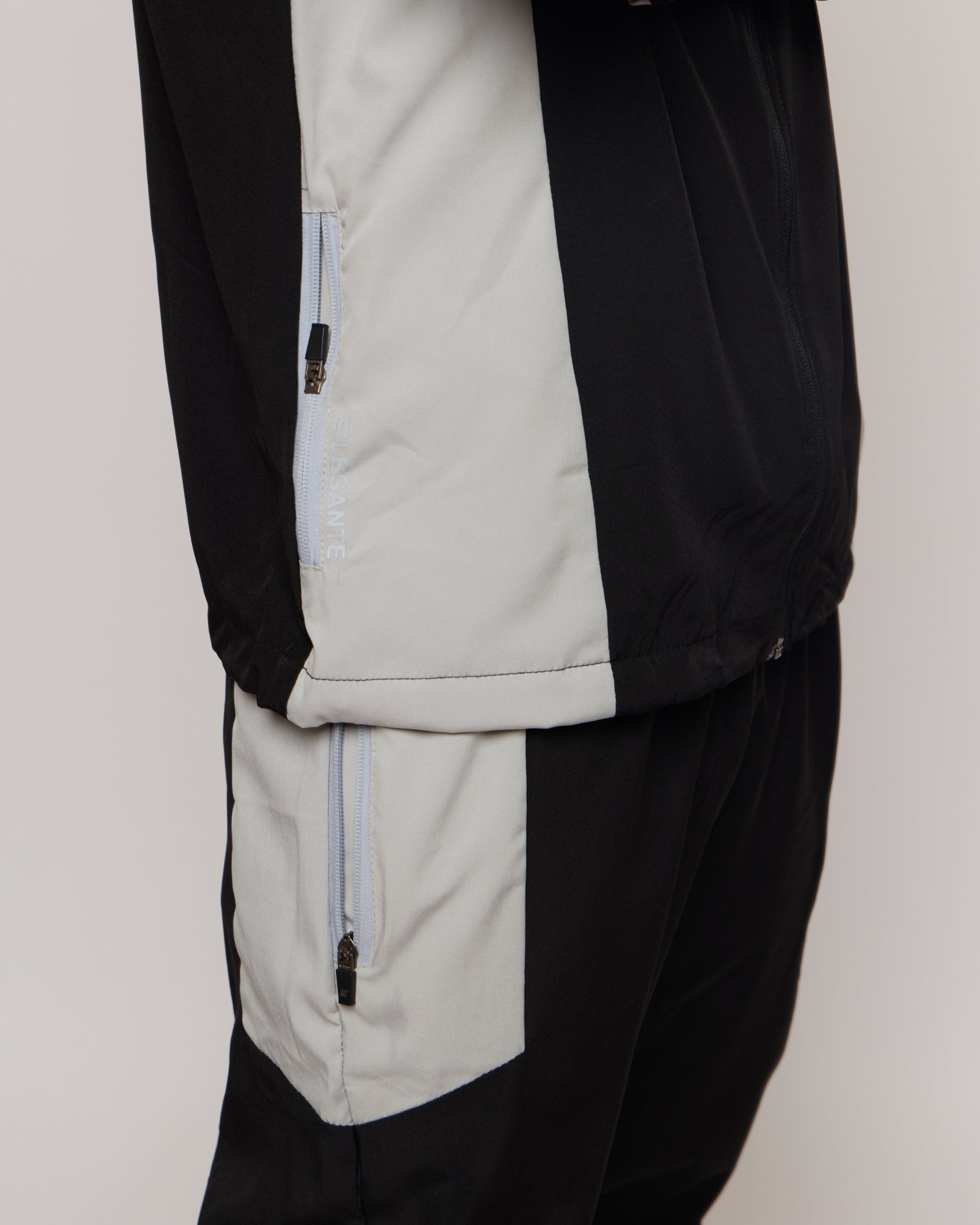 Black and gray jacket with zipper details on a neutral background
