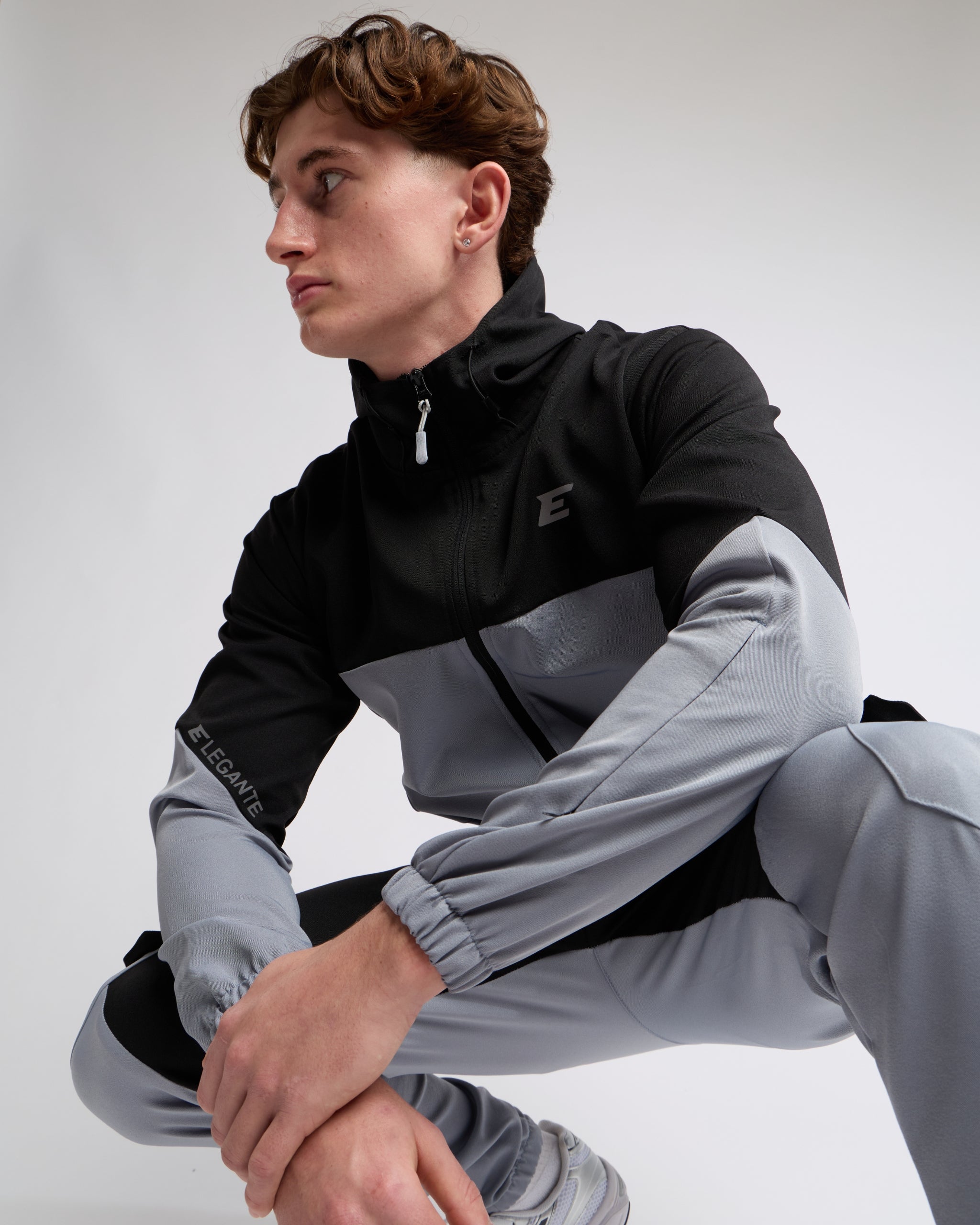 elegante wearing a black and gray tracksuit with a elegante brand logo on a light gray background