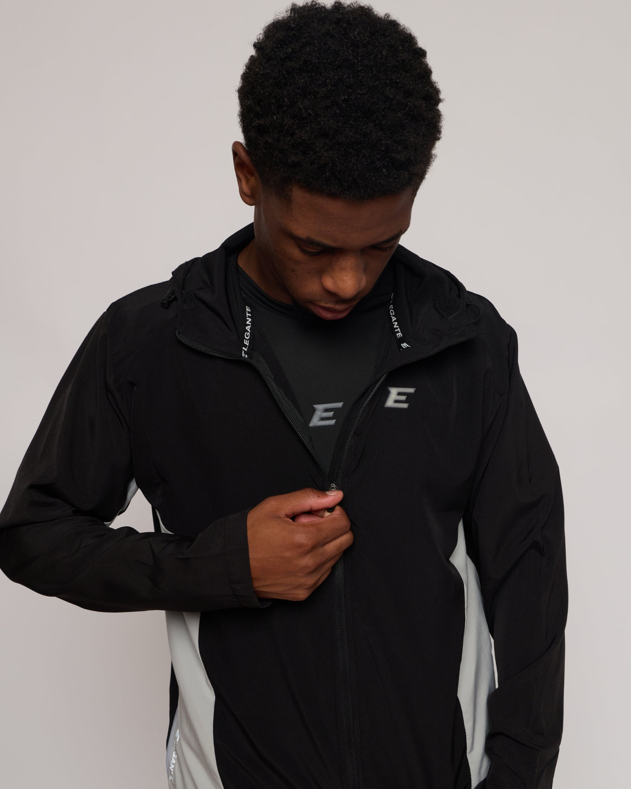 man wearing a black jacket with a elegante logo on a plain background