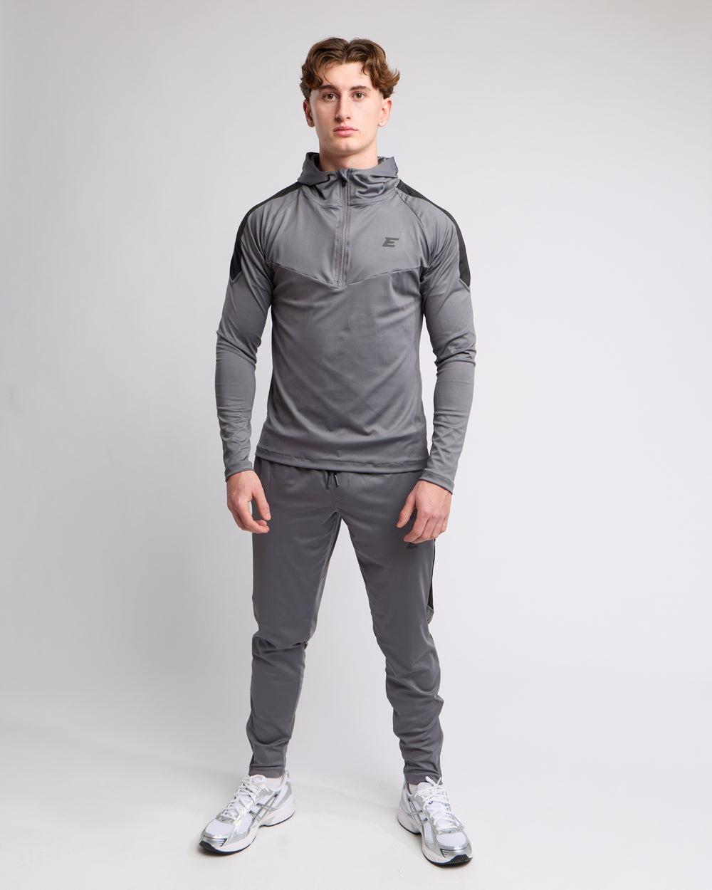 man wearing a gray tracksuit set on a light gray background