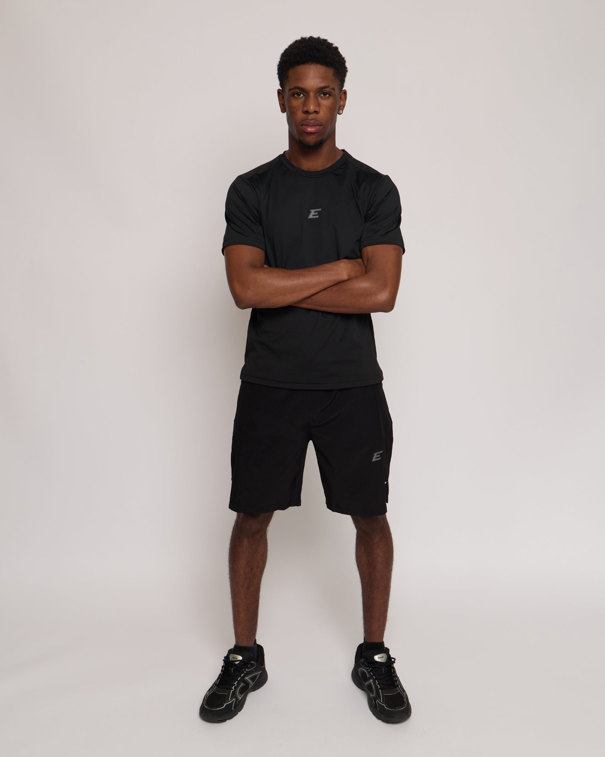 Man wearing a black athletic shorts and t-shirt outfit with a black 'E' brand logo on white background