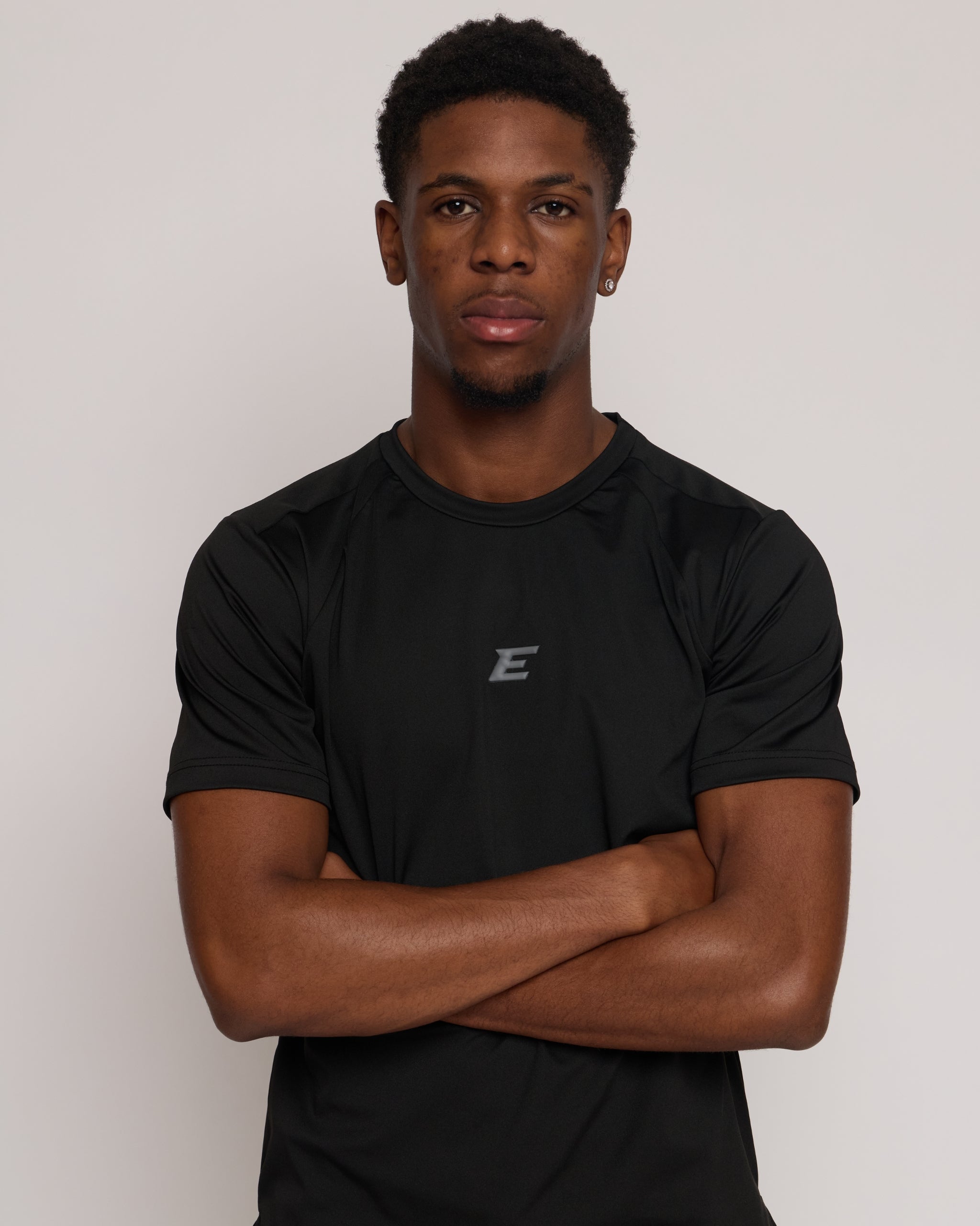 Man wearing a black athletic shorts and t-shirt outfit with a grey 'E' brand logo on white background