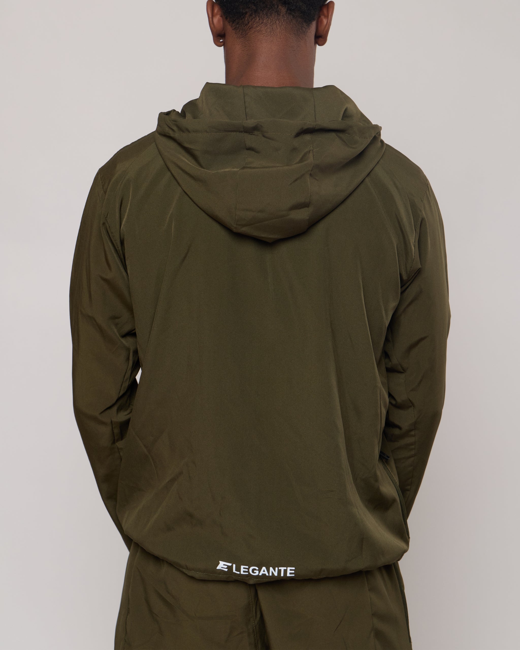man wearing an olive green jacket with a hood on a light gray background