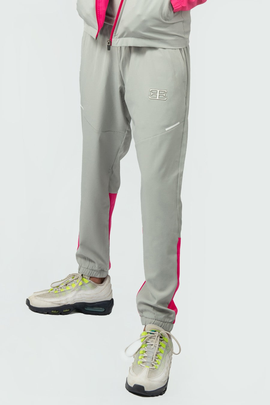 man wearing pink and grey tracksuit pant joggers with a elegante logo on a white background