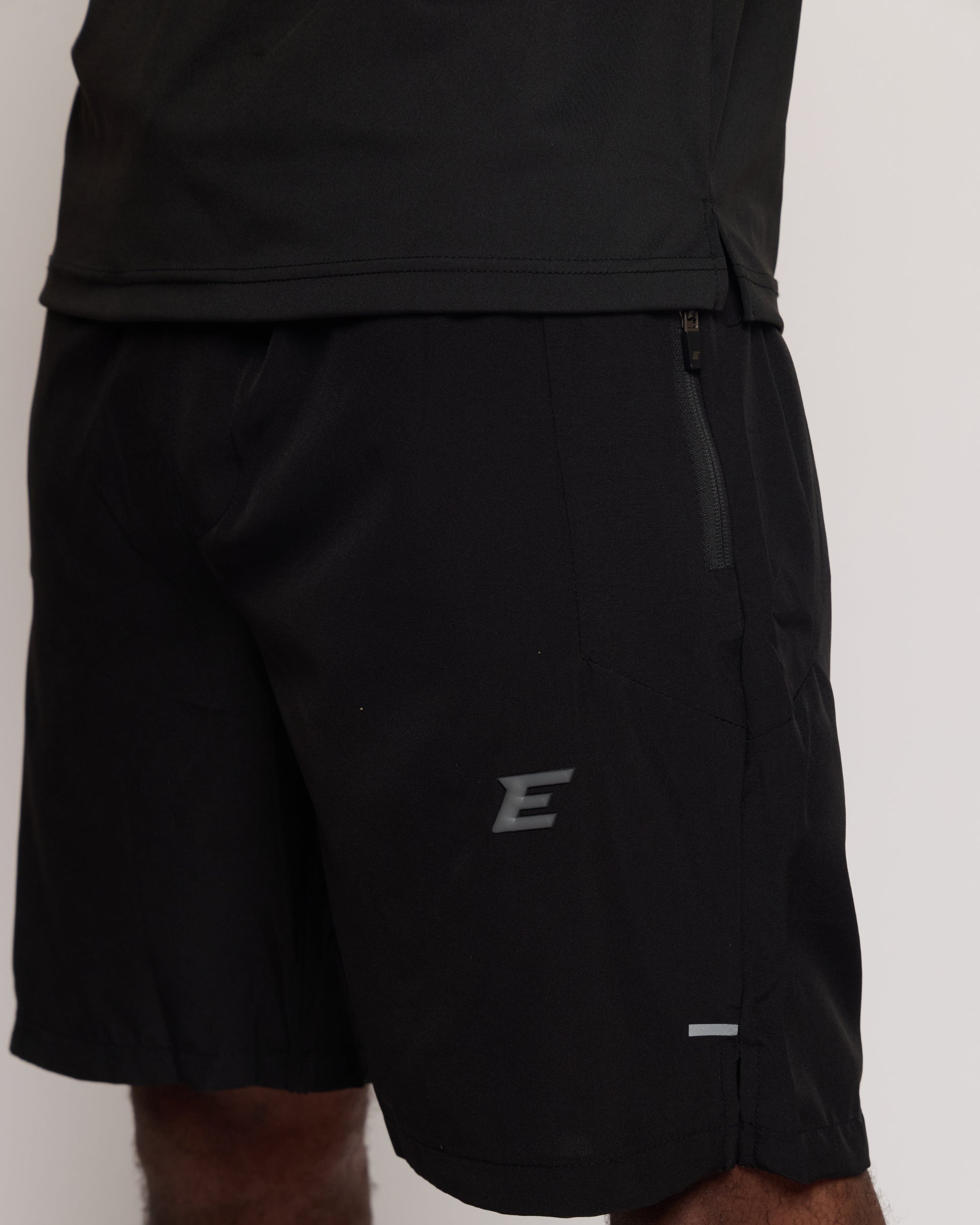 Black athletic shorts with an E logo on a light gray background