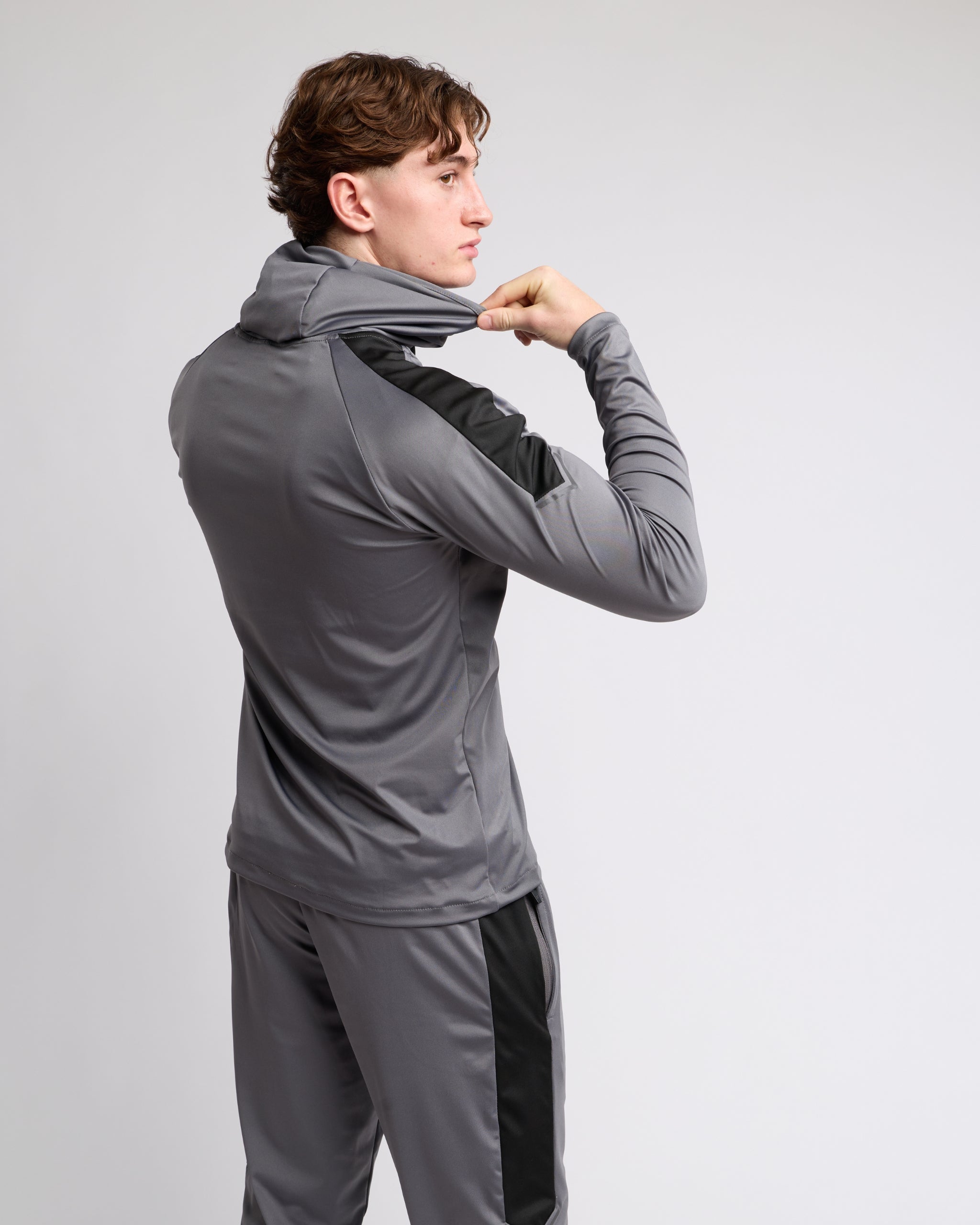 man wearing a gray tracksuit set on a light gray background