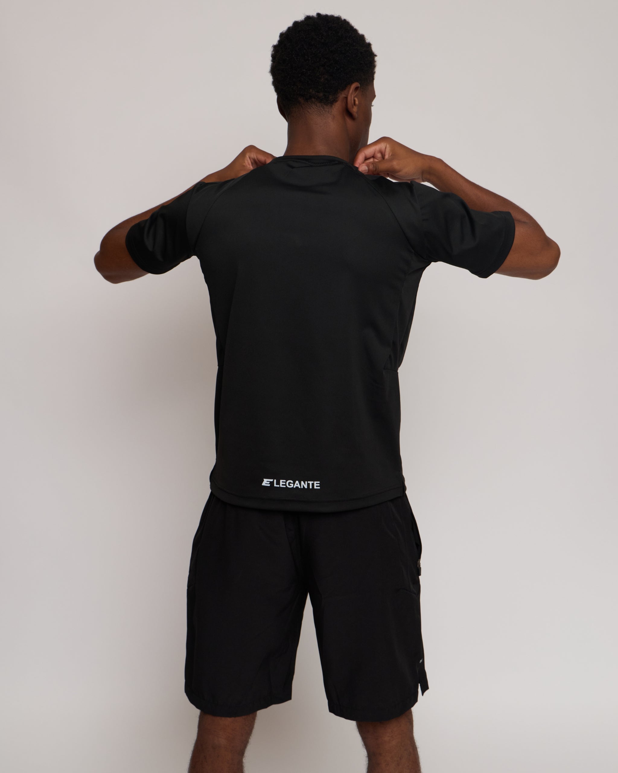Man wearing a black athletic outfit with 'elegante' branding on a white background
