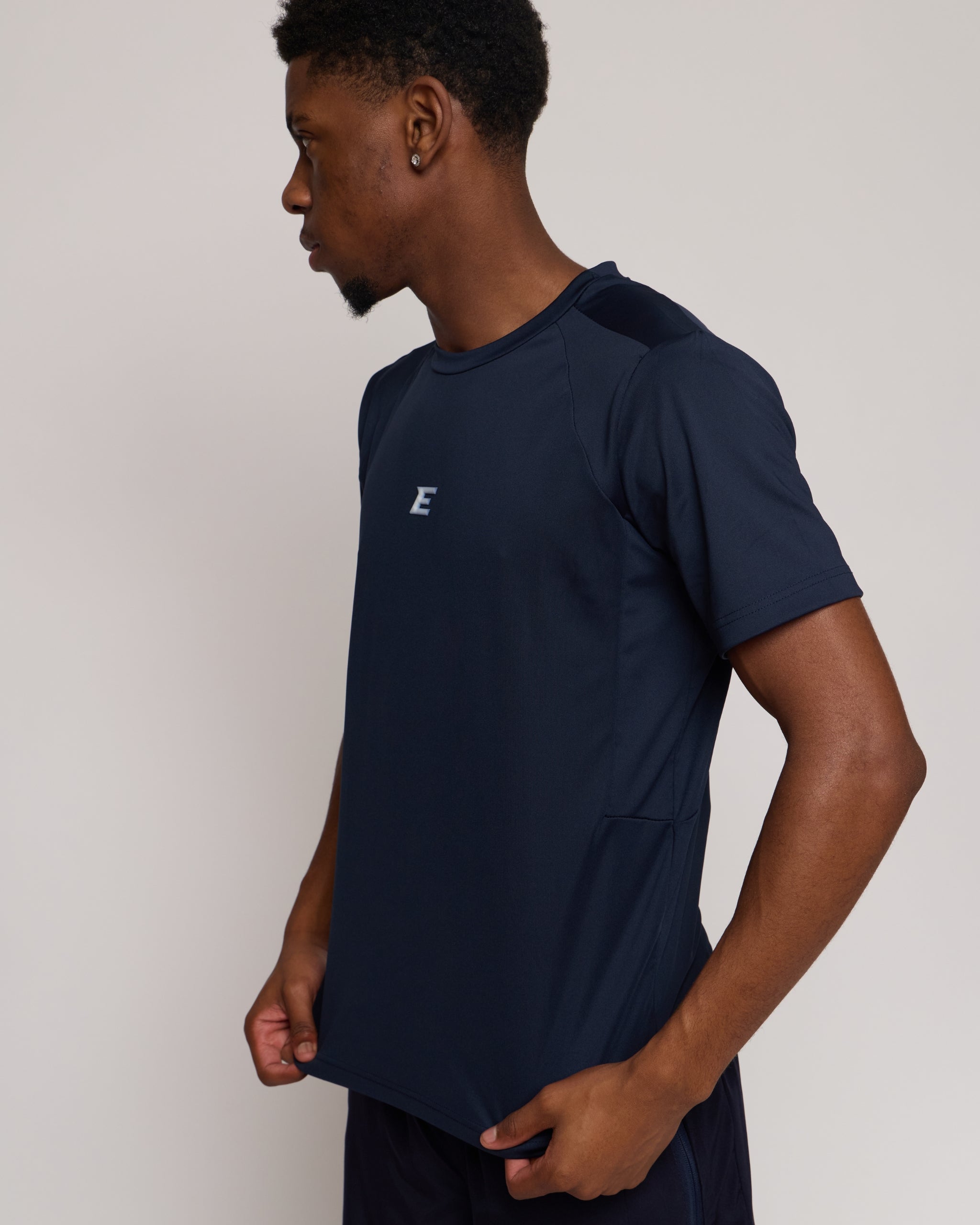 Man wearing a navy athletic shorts and t-shirt outfit with a white 'E' brand logo on white background