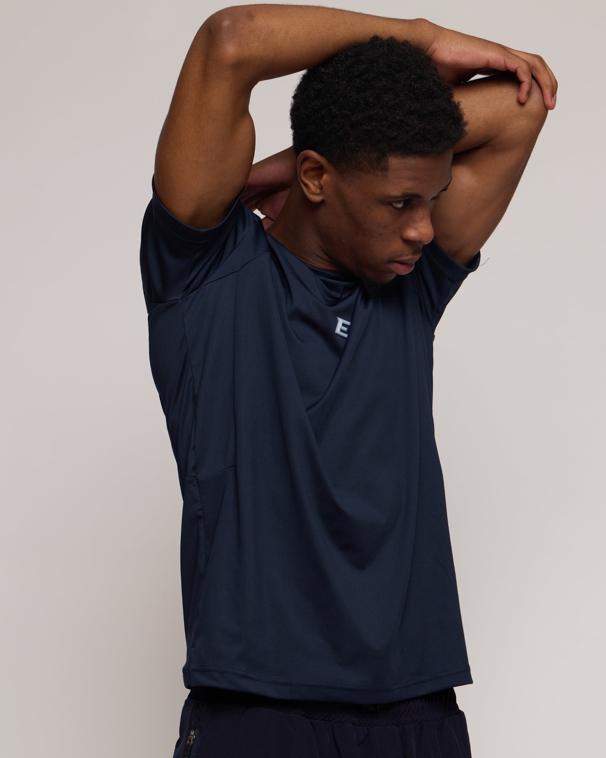 Man wearing a navy athletic shorts and t-shirt outfit with a white 'E' brand logo on white background