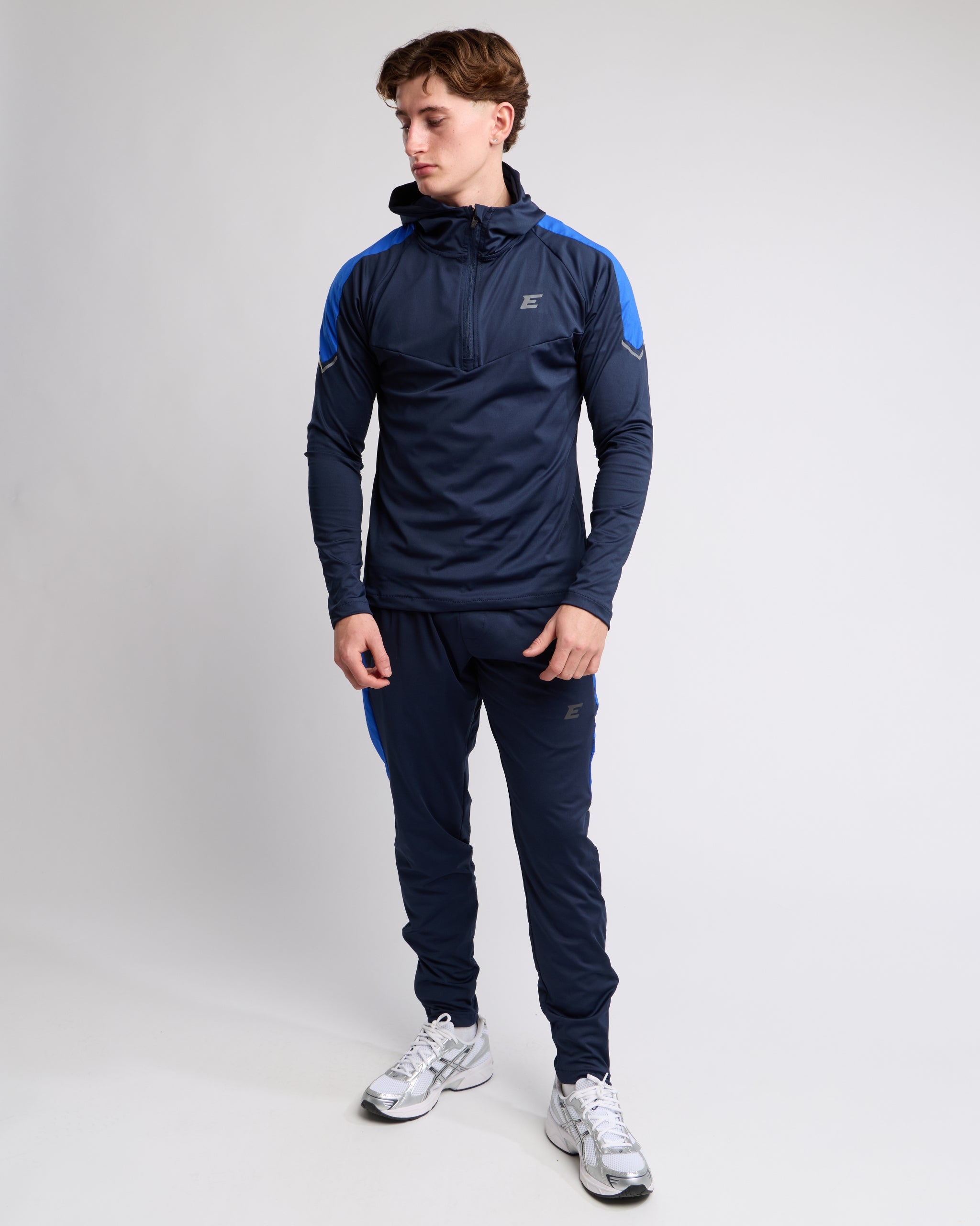 Man wearing a navy tracksuit with blue accents on a white background