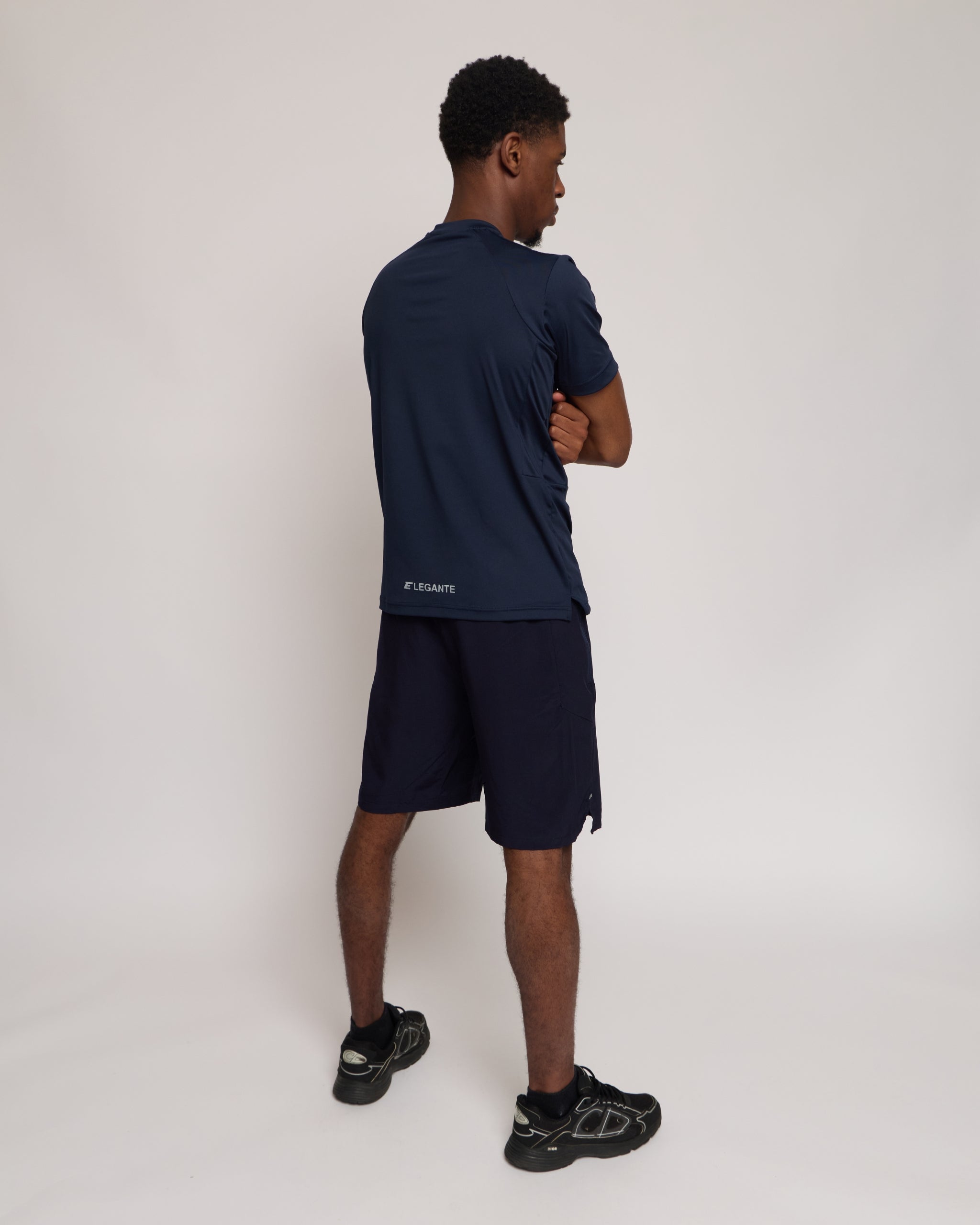 Man wearing a navy athletic shorts and t-shirt outfit with a white 'E' brand logo on white background