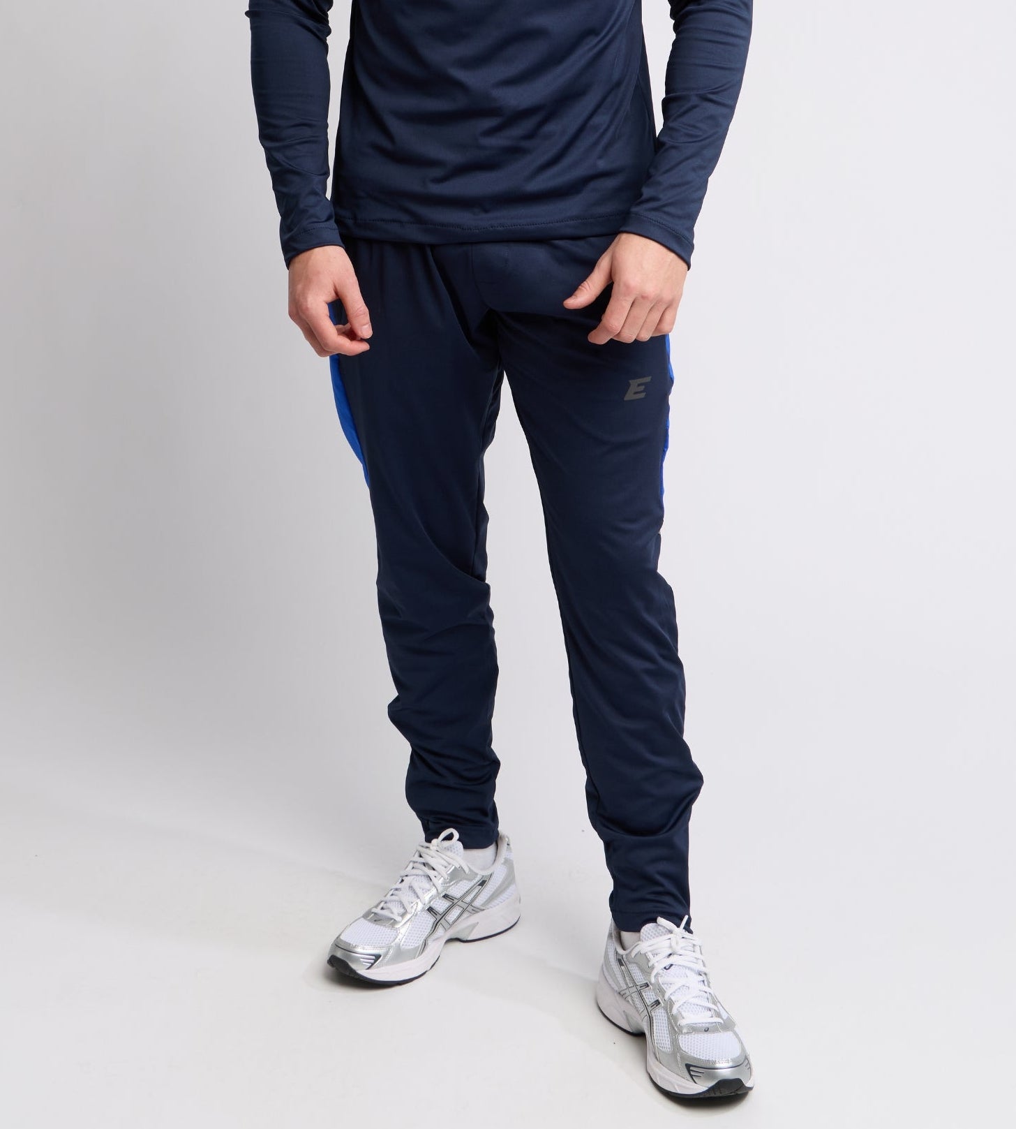 Person wearing a navy tracksuit with blue accents on a white background