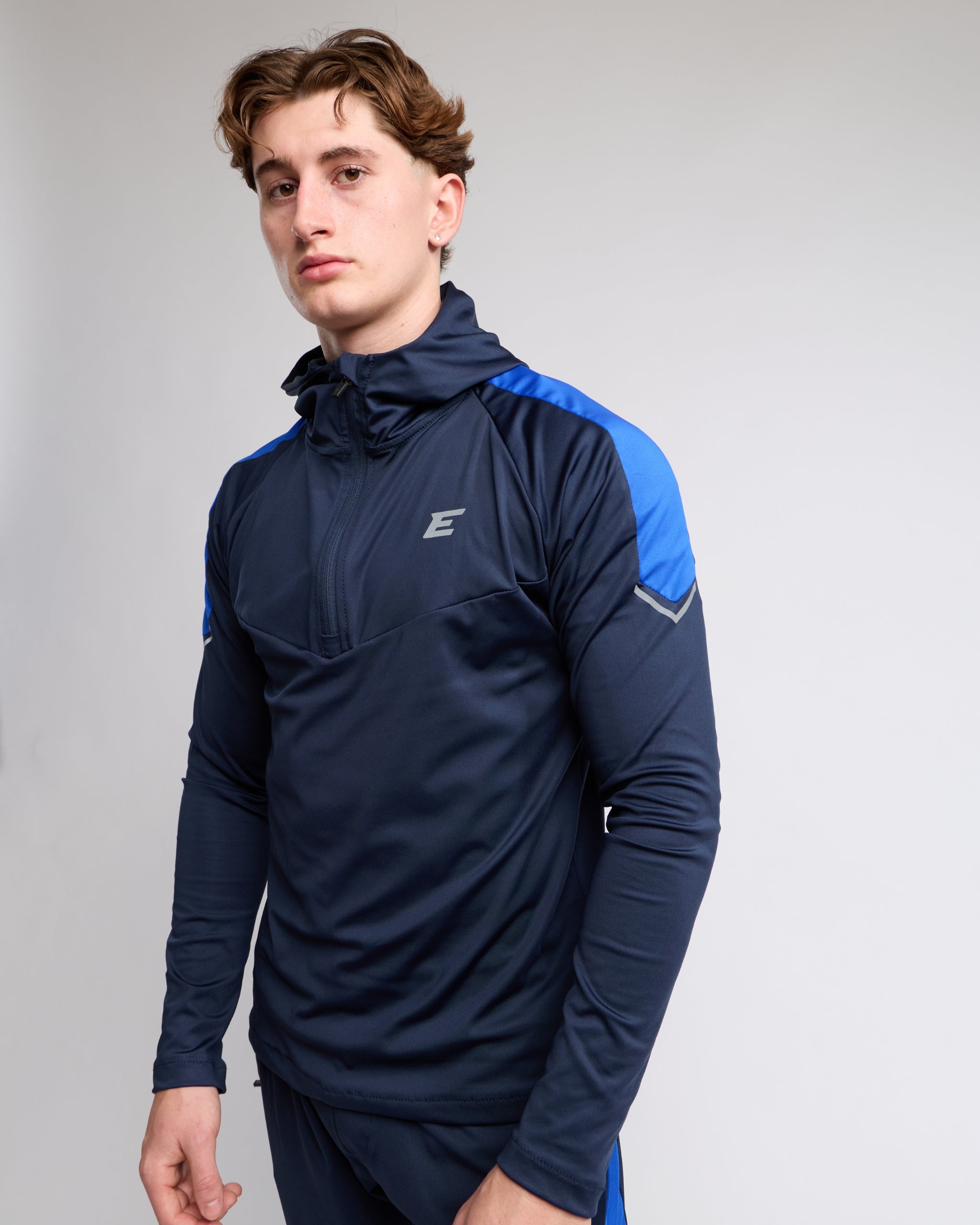 man wearing a navy and blue athletic zip top with elegante brand logo on a gray background