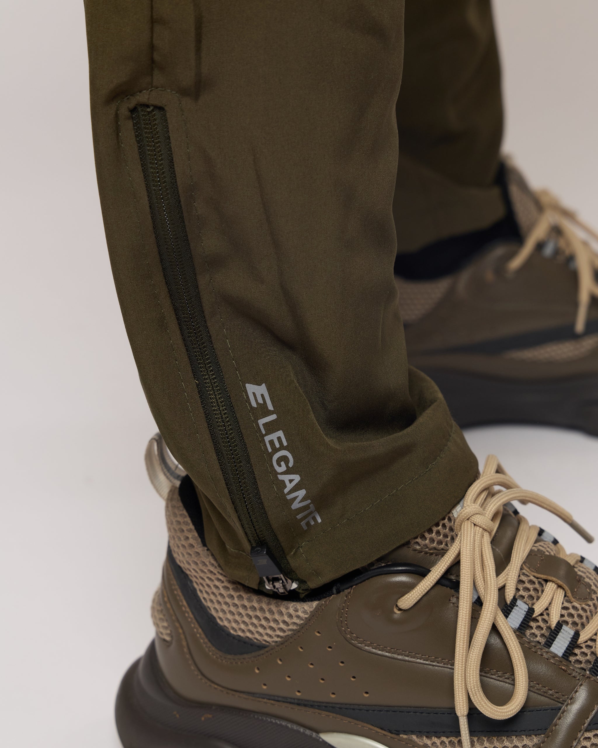 green tracksuit joggers with elegante logo on a plain background