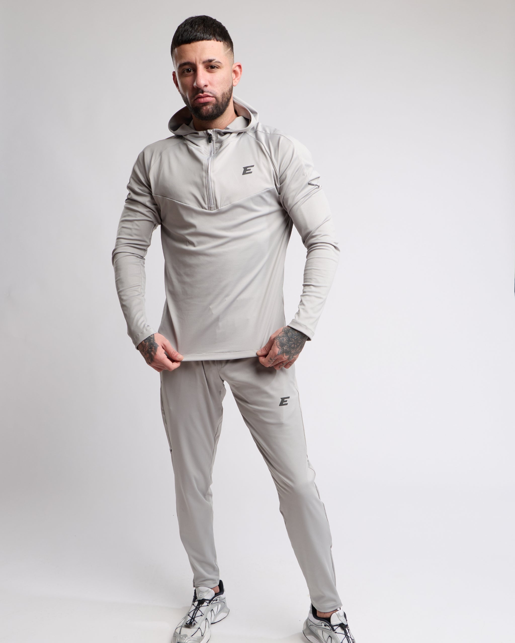 Man wearing a gray tracksuit with a brand logo on a white background